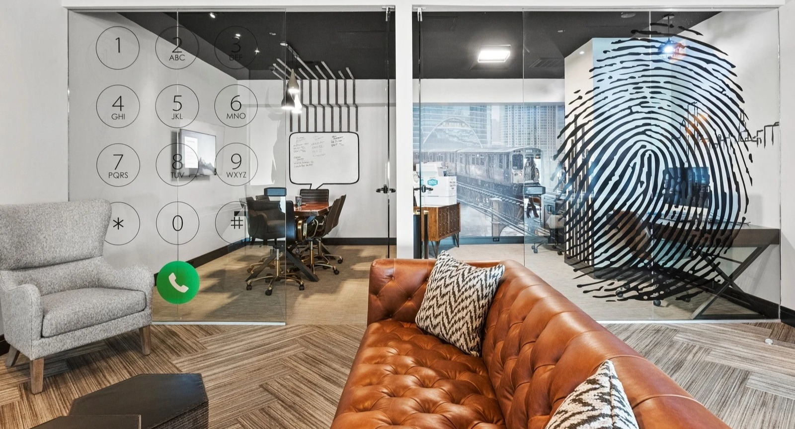 Modern private work pods at Park Michigan in Chicago, featuring glass walls with graphic designs, comfortable seating, and desk space