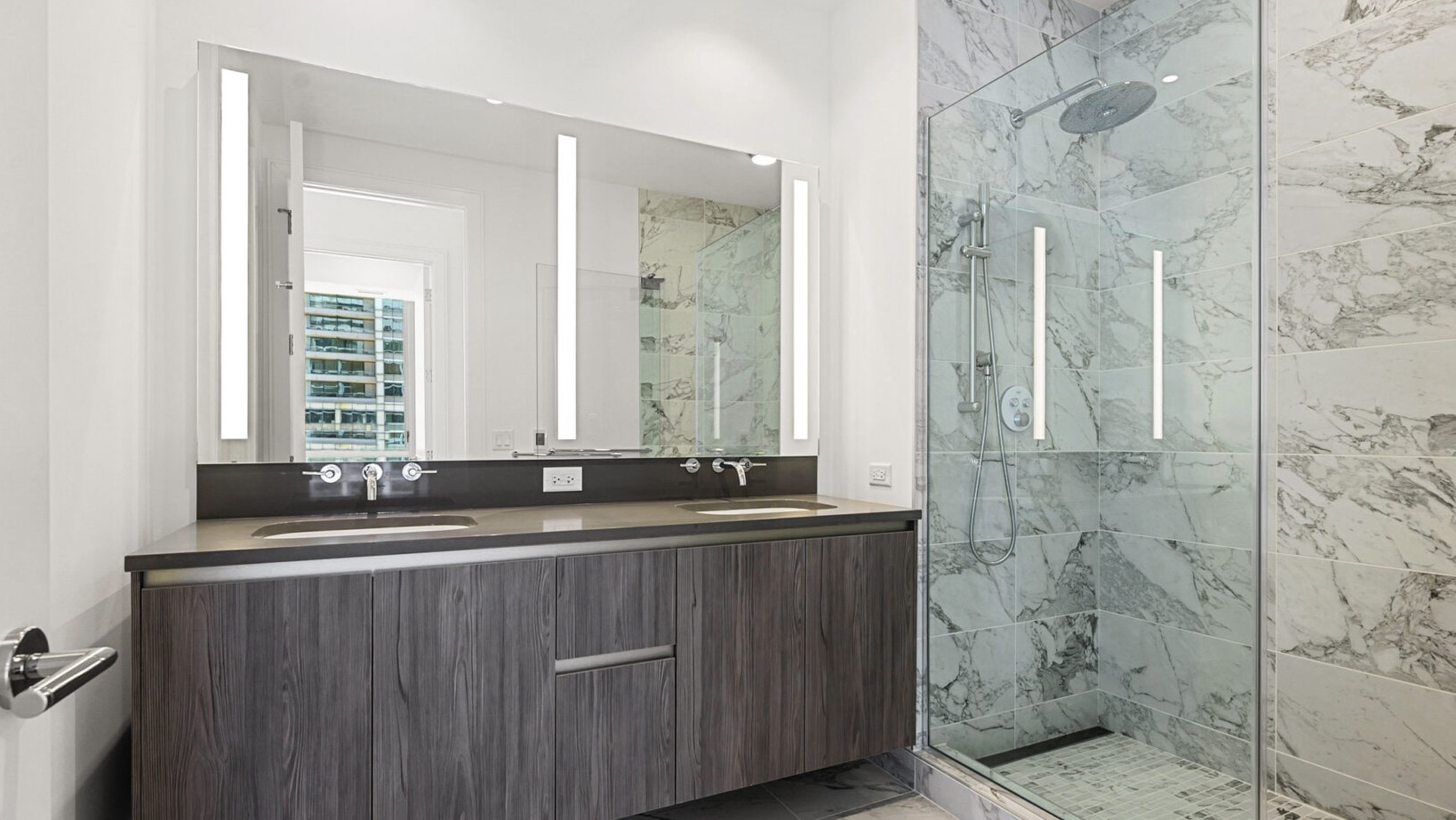 Luxurious bathroom with a double vanity, modern fixtures, and a spacious walk-in shower with marble tiling at Parkline Chicago in Chicago