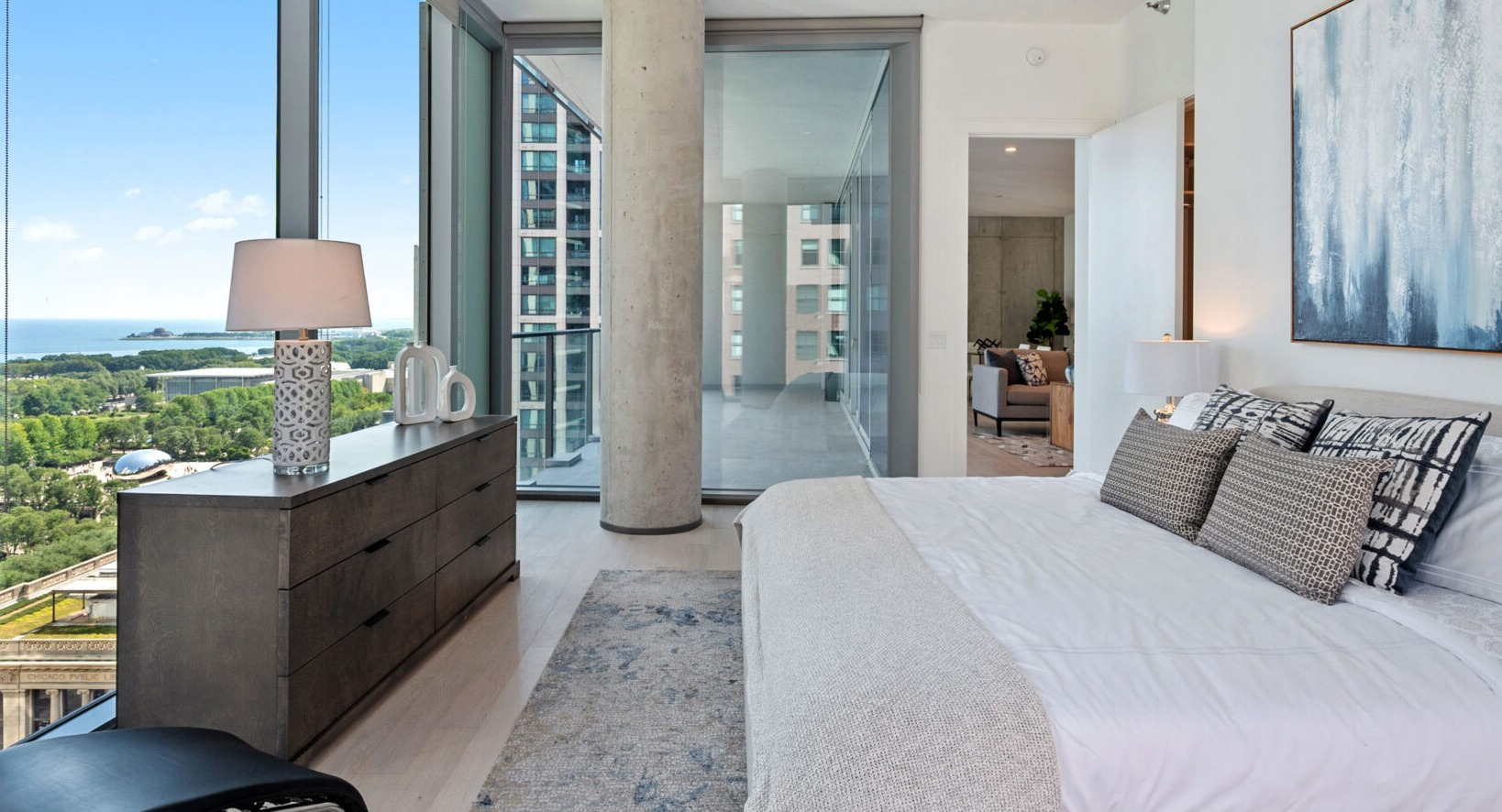 Elegant bedroom with a large bed, abstract art, and floor-to-ceiling windows offering spectacular lake and city views at Parkline Chicago in Chicago