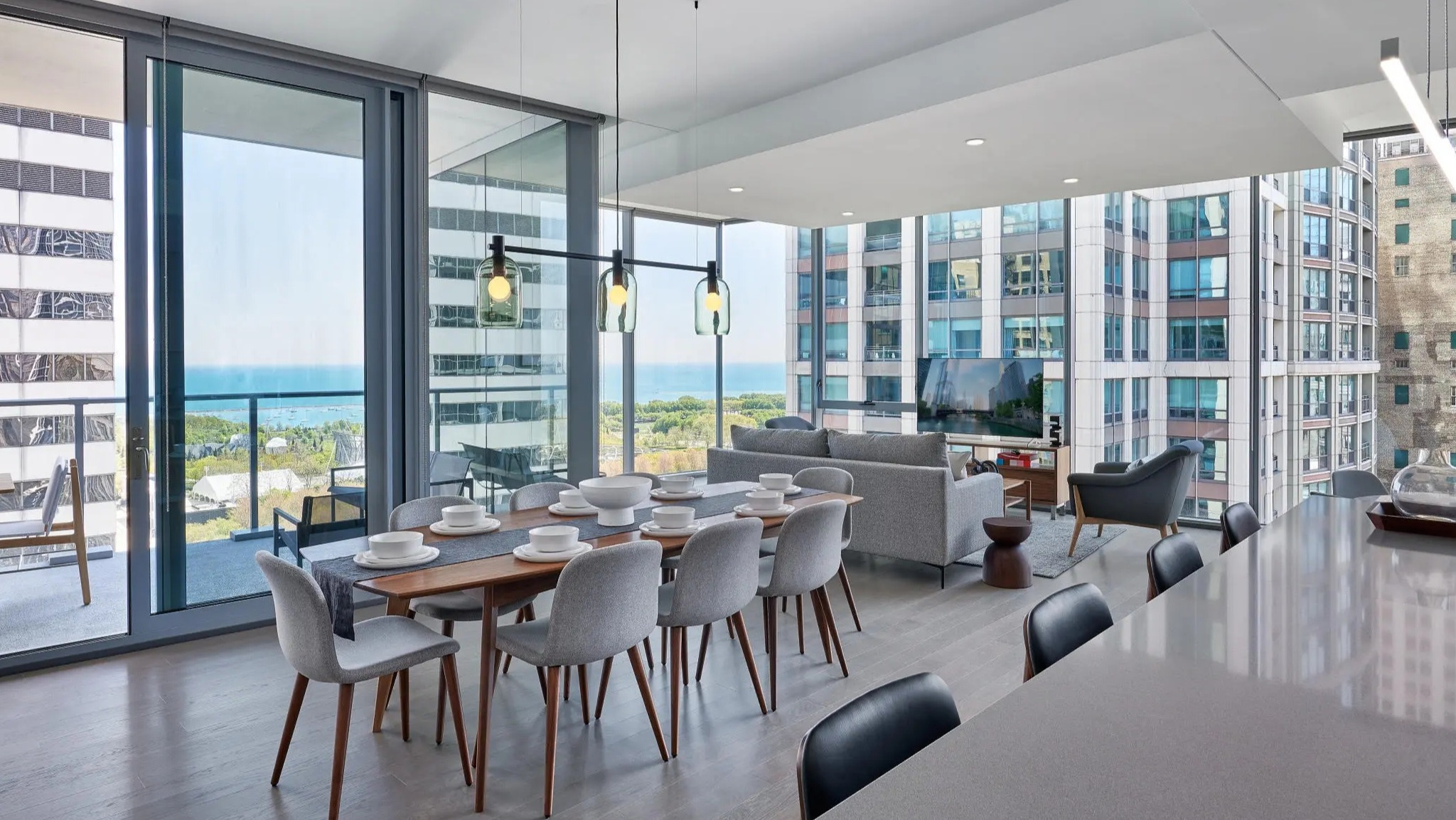 Spacious dining and living area with stunning lake views, modern furniture, and an open-concept kitchen at Parkline Chicago in Chicago