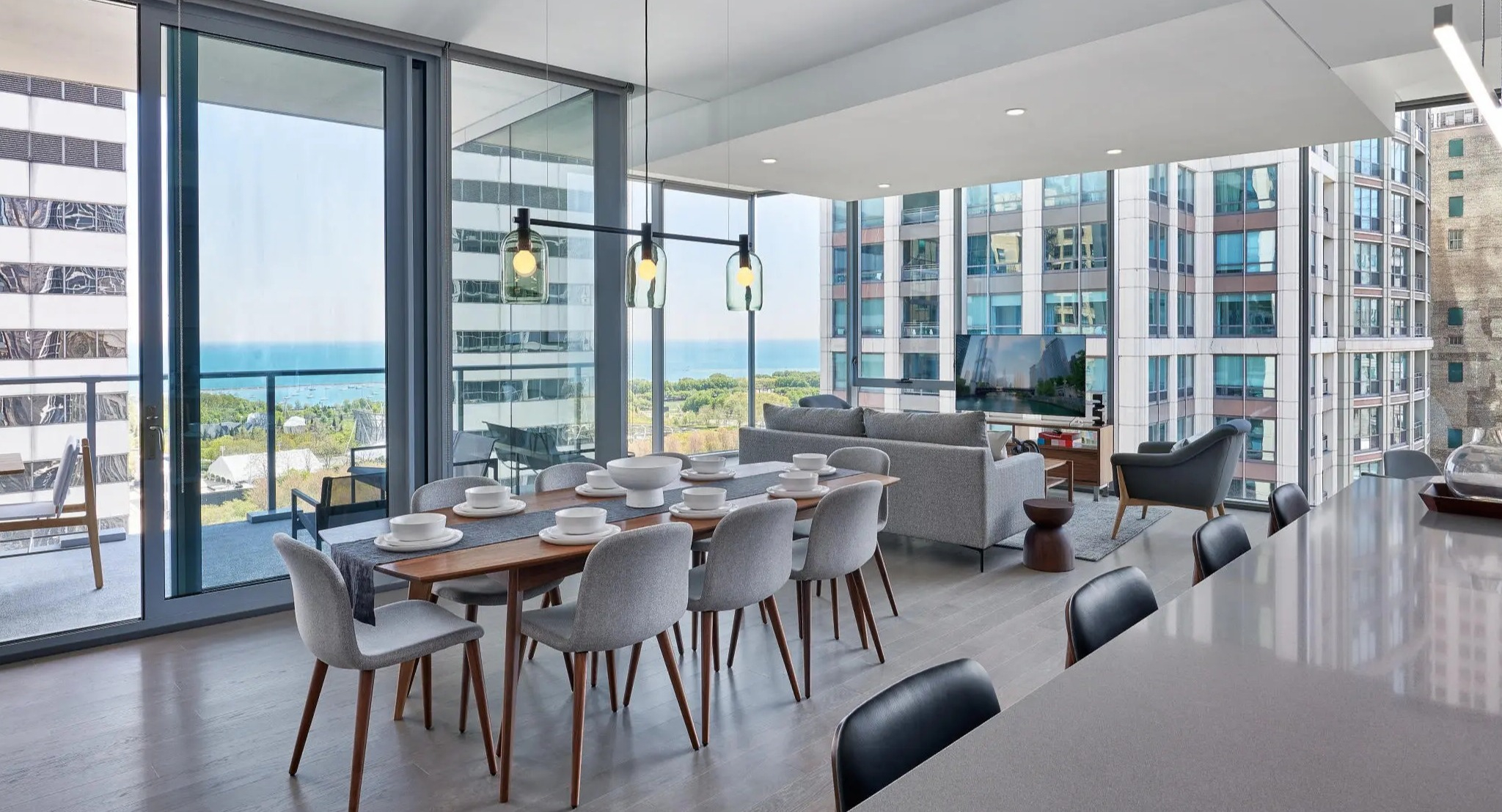 Spacious dining and living area with stunning lake views, modern furniture, and an open-concept kitchen at Parkline Chicago in Chicago