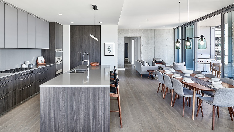 Open-concept kitchen, dining, and lounge area with dark wood cabinetry, modern lighting, and a large dining table at Parkline Chicago in Chicago