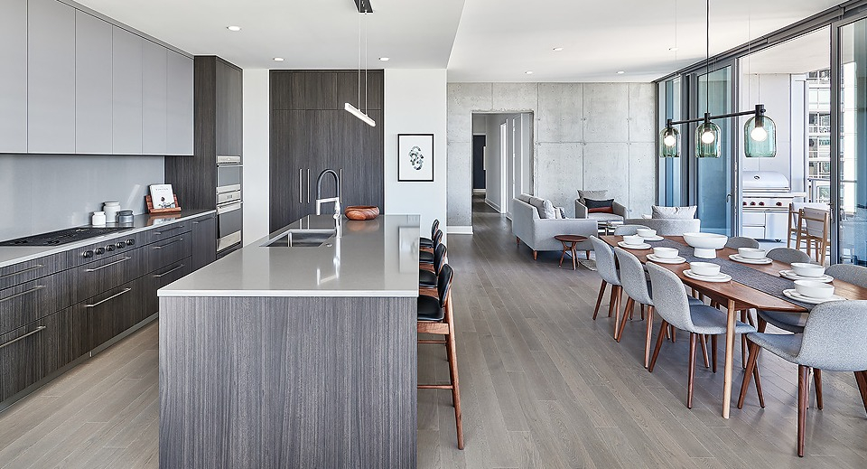 Open-concept kitchen, dining, and lounge area with dark wood cabinetry, modern lighting, and a large dining table at Parkline Chicago in Chicago