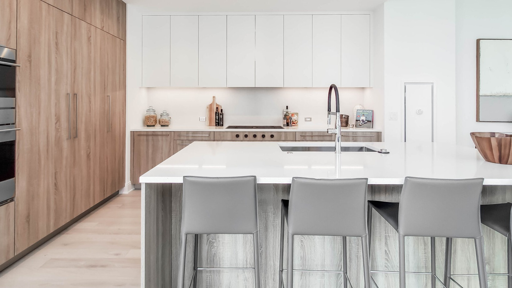 Elegant kitchen with a large island, wood and white cabinetry, integrated appliances, and bar seating at Parkline Chicago in Chicago