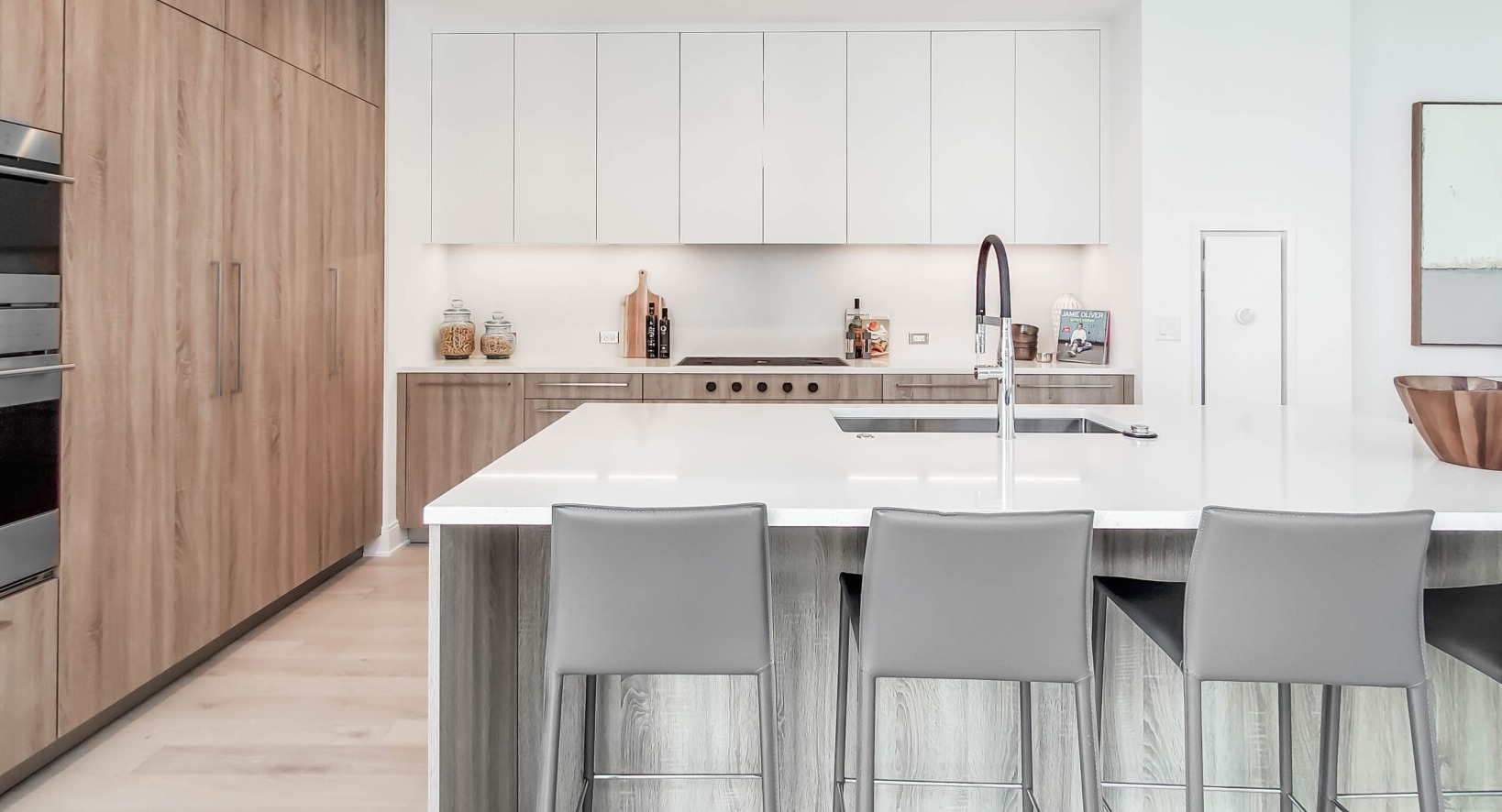 Elegant kitchen with a large island, wood and white cabinetry, integrated appliances, and bar seating at Parkline Chicago in Chicago