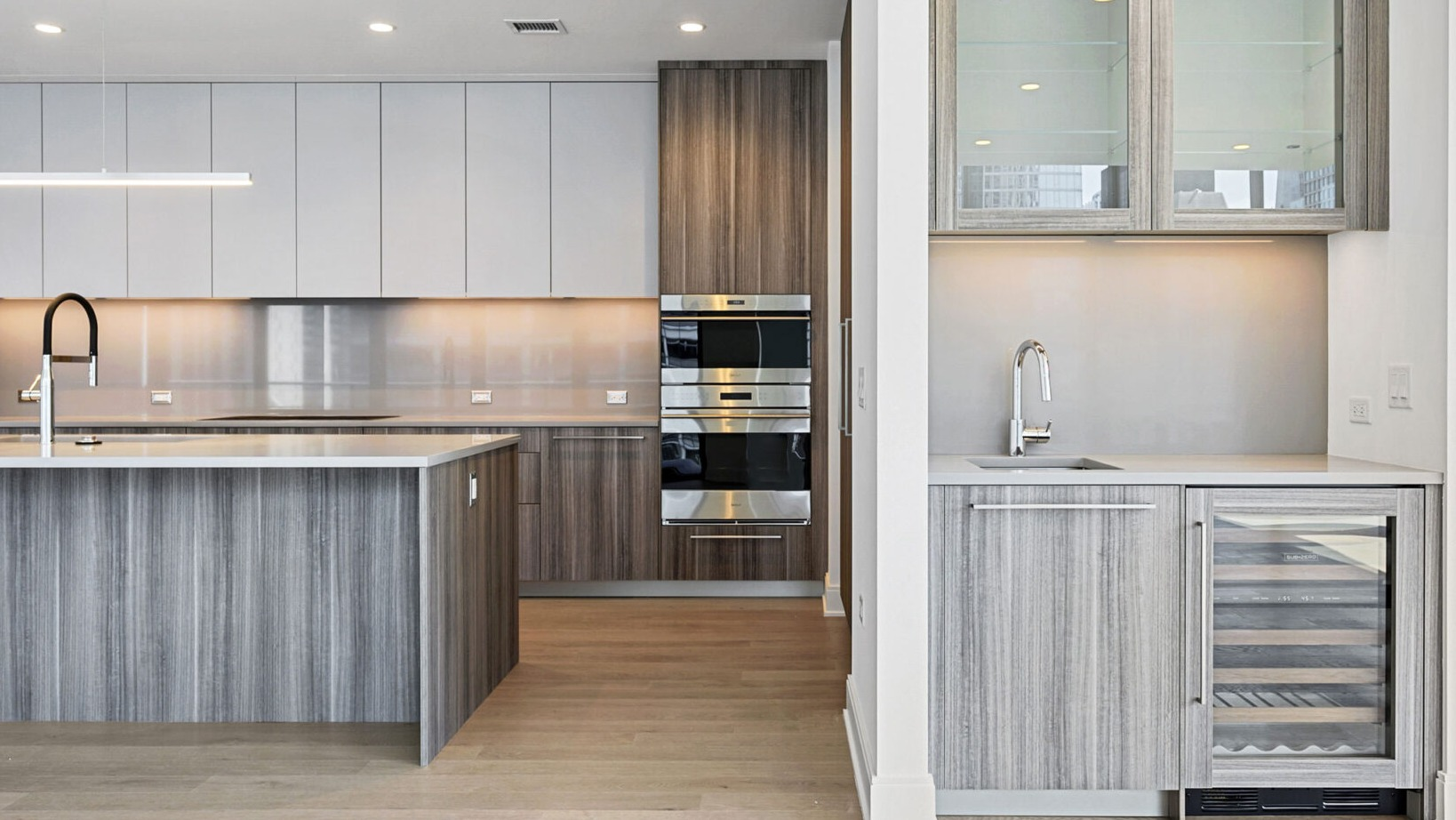Sophisticated kitchen with wood and white cabinetry, built-in appliances, and a dedicated wine cooler at Parkline Chicago in Chicago