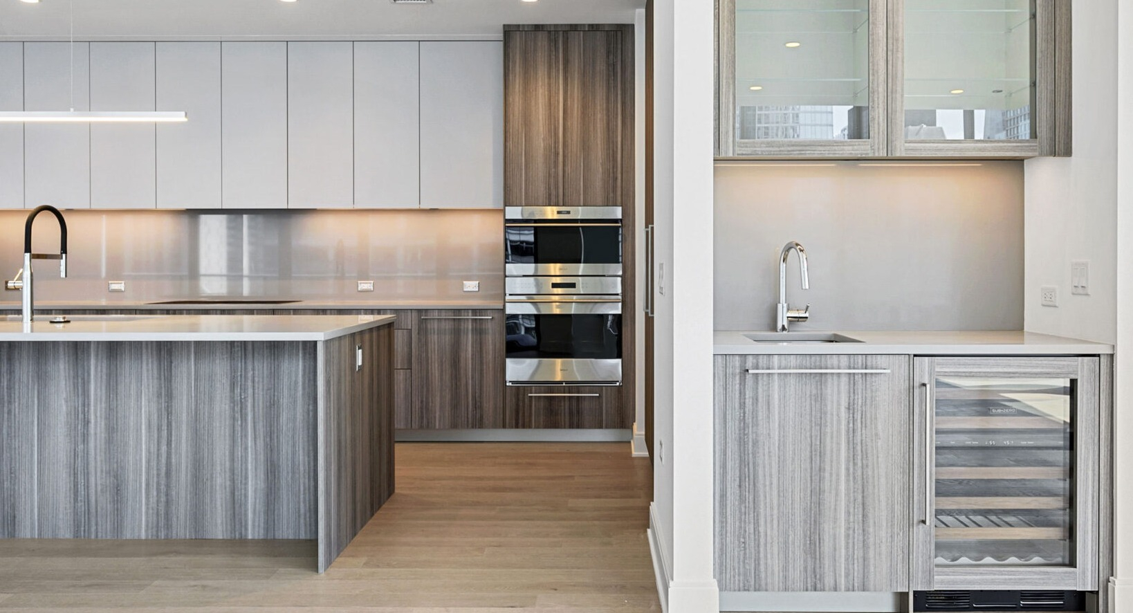 Sophisticated kitchen with wood and white cabinetry, built-in appliances, and a dedicated wine cooler at Parkline Chicago in Chicago