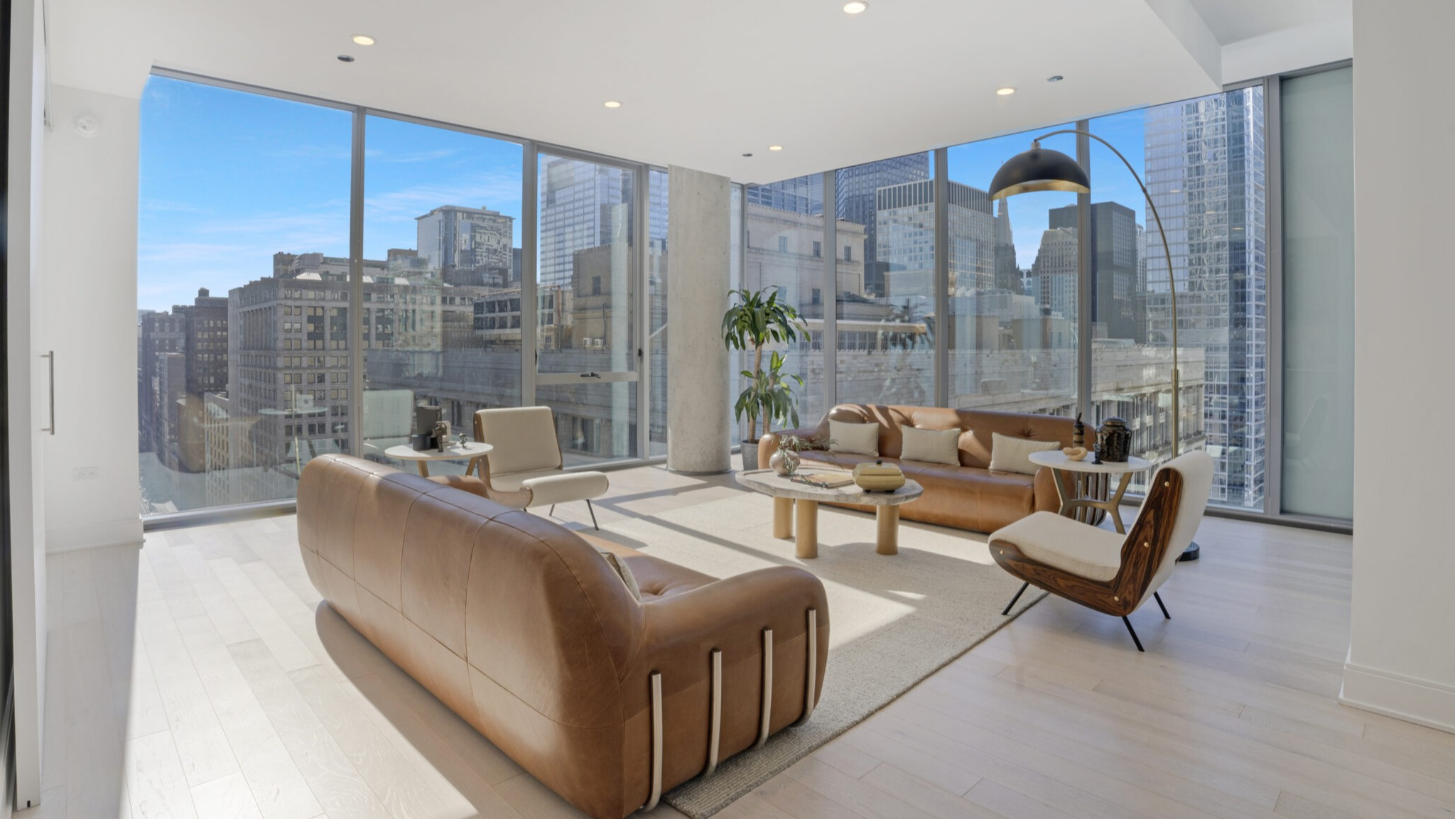 Spacious living room with stylish leather sofas and panoramic city views through floor-to-ceiling windows at Parkline Chicago in Chicago