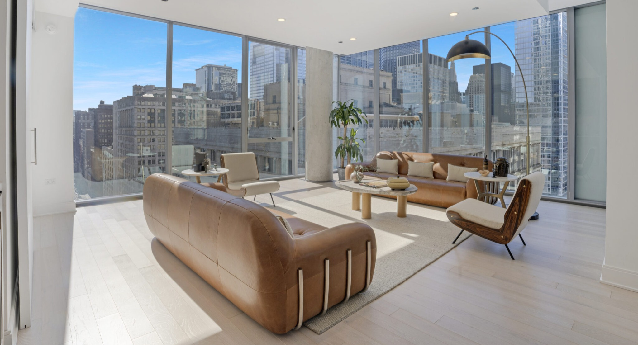 Spacious living room with stylish leather sofas and panoramic city views through floor-to-ceiling windows at Parkline Chicago in Chicago