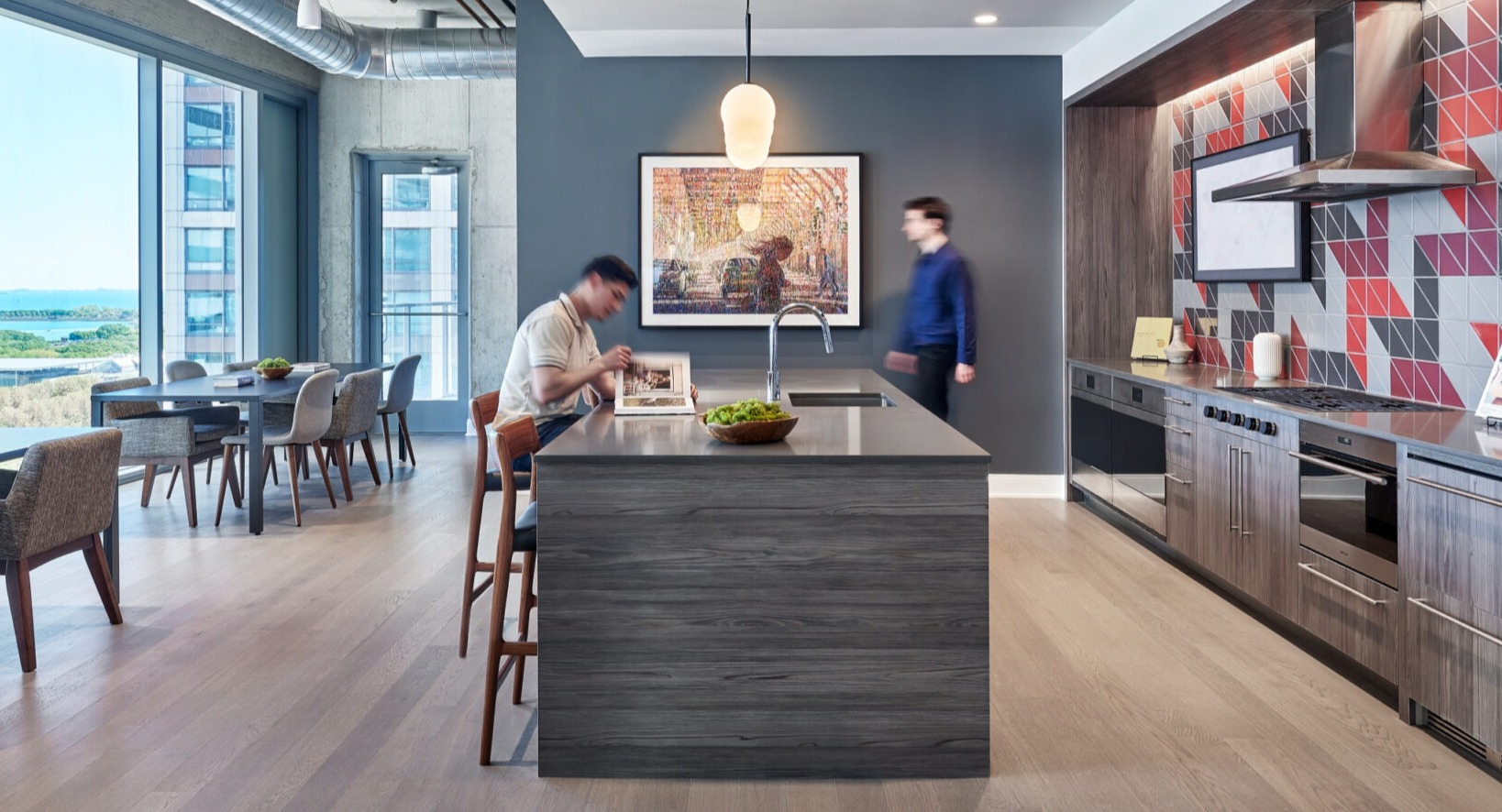 Chic resident kitchen and dining area with modern appliances, an island, and views of the city and lake at Parkline Chicago in Chicago