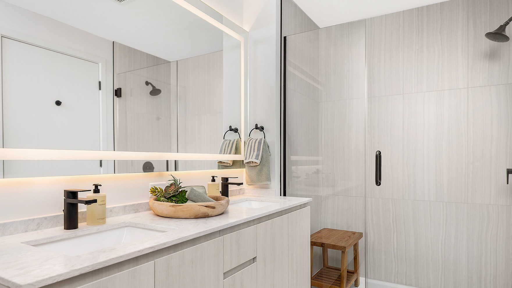Luxurious apartment bathroom at Parq Fulton in Chicago, featuring a double vanity, modern fixtures, and a spacious walk-in shower