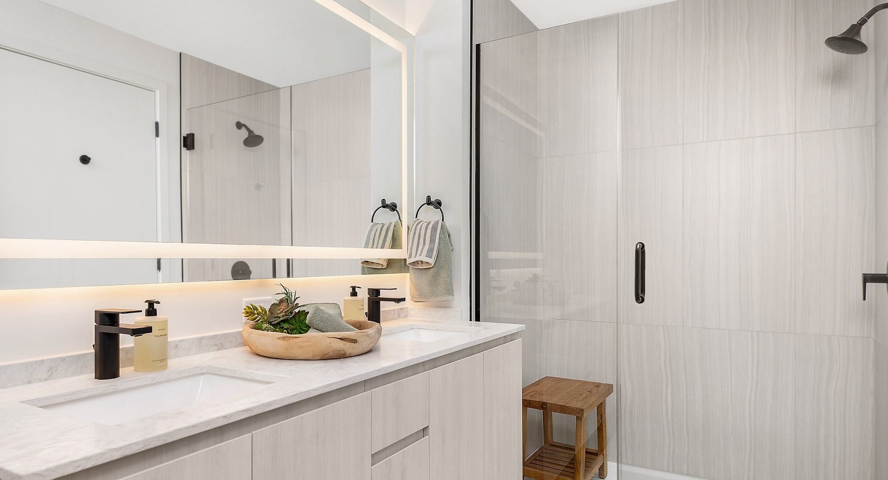 Luxurious apartment bathroom at Parq Fulton in Chicago, featuring a double vanity, modern fixtures, and a spacious walk-in shower