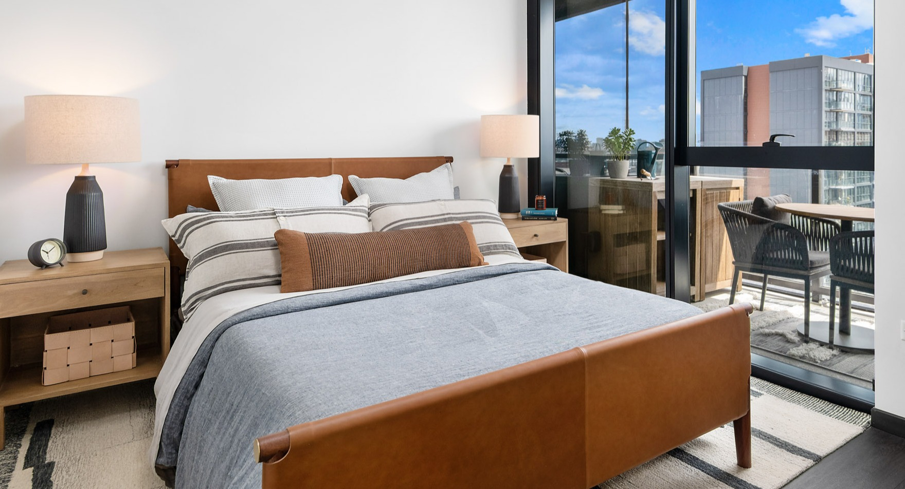 Chic apartment bedroom at Parq Fulton in Chicago, featuring a comfortable bed and direct access to a private balcony with city views