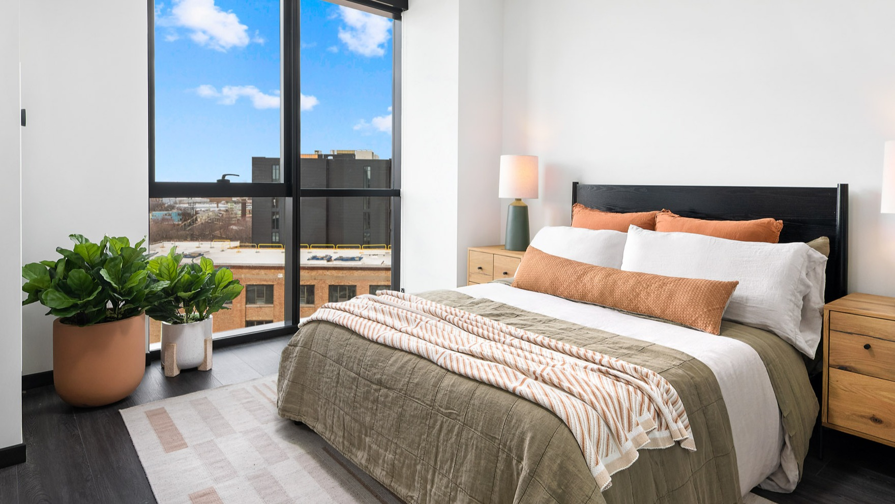 Bright and inviting apartment bedroom at Parq Fulton in Chicago, featuring a comfortable bed, stylish decor, and large windows