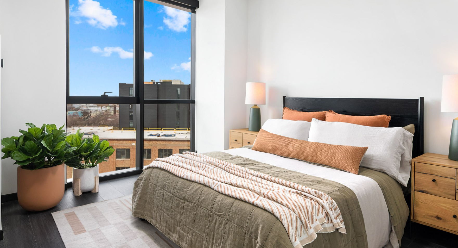 Bright and inviting apartment bedroom at Parq Fulton in Chicago, featuring a comfortable bed, stylish decor, and large windows