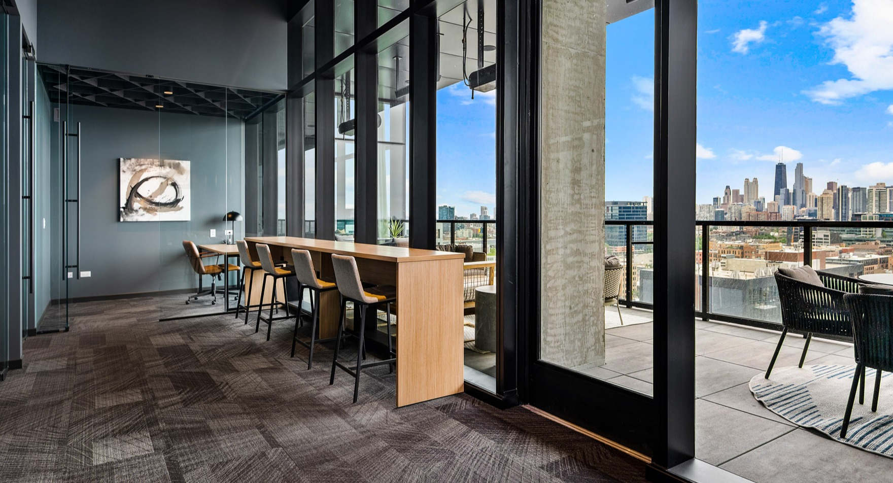 Dynamic coworking space at Parq Fulton in Chicago, featuring collaborative workstations and an adjacent balcony with city views