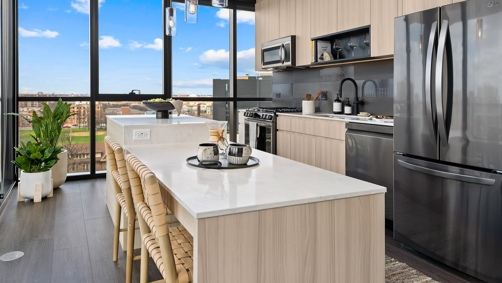 Bright and modern apartment kitchen at Parq Fulton in Chicago, featuring light wood cabinetry, a large island, and city views