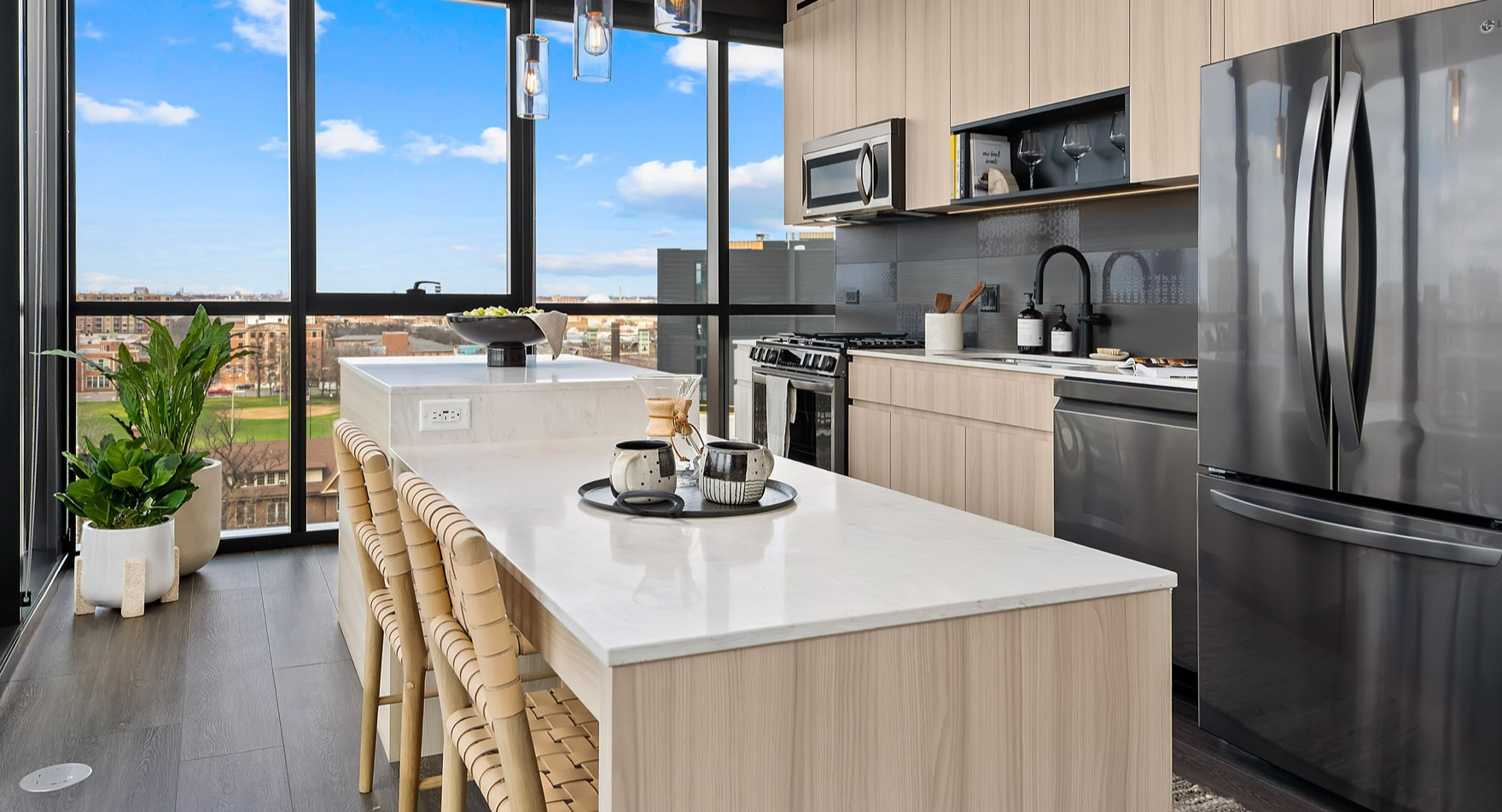 Bright and modern apartment kitchen at Parq Fulton in Chicago, featuring light wood cabinetry, a large island, and city views