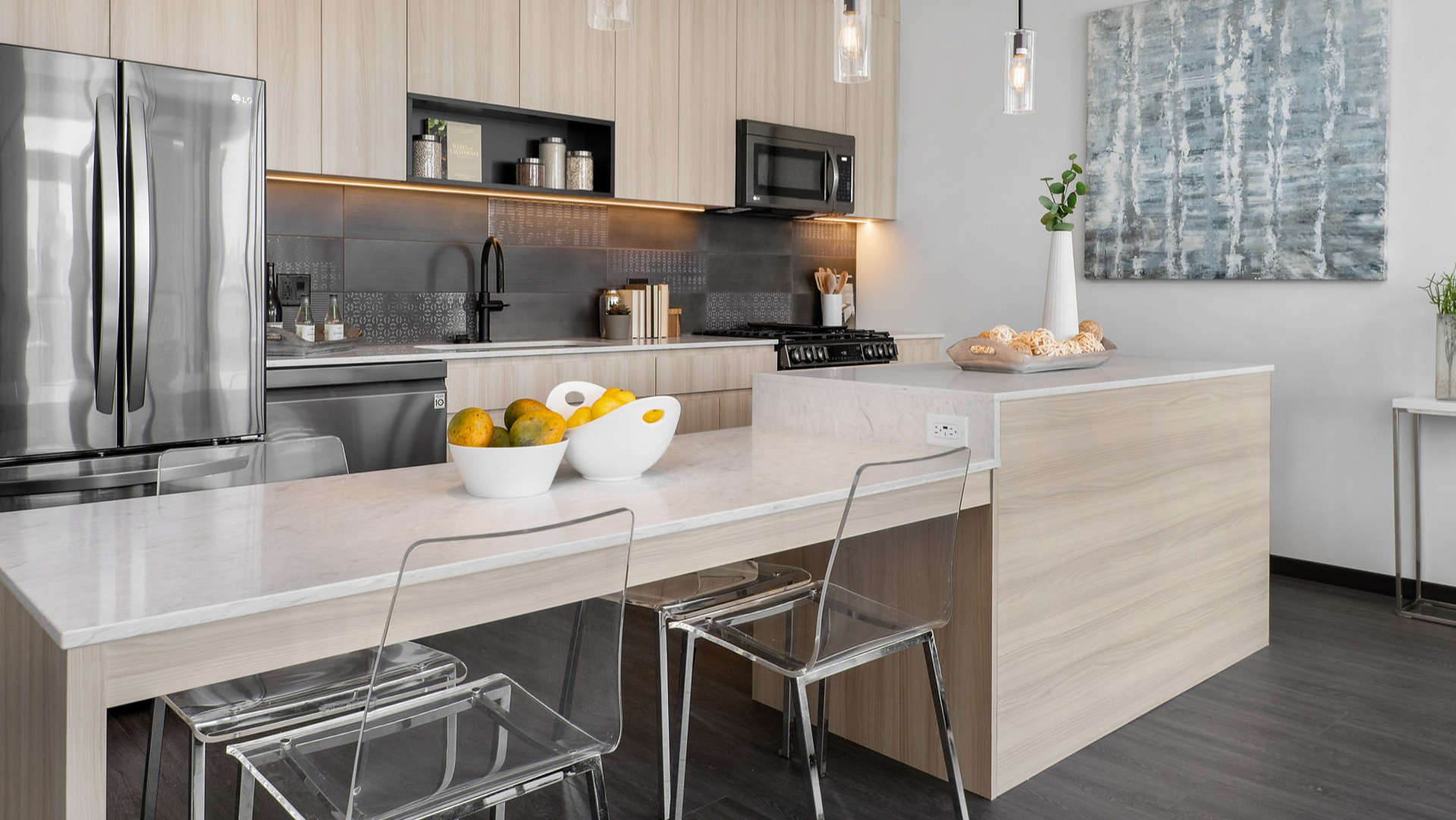 Modern apartment kitchen at Parq Fulton in Chicago, featuring light wood cabinets, a large island with seating, and stainless steel appliances