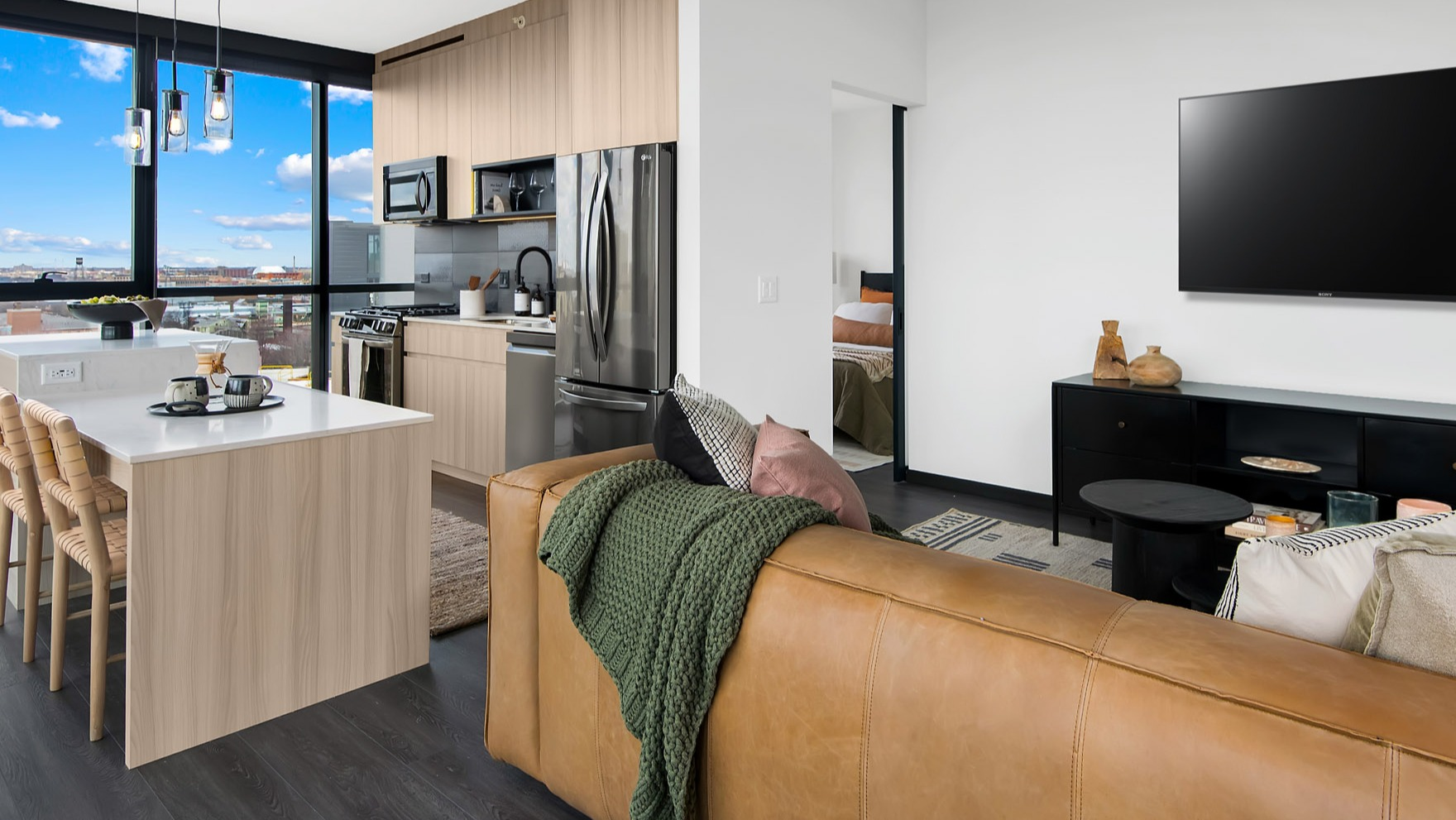 Modern open-concept kitchen and living area at Parq Fulton in Chicago, featuring a large island, comfortable seating, and city views
