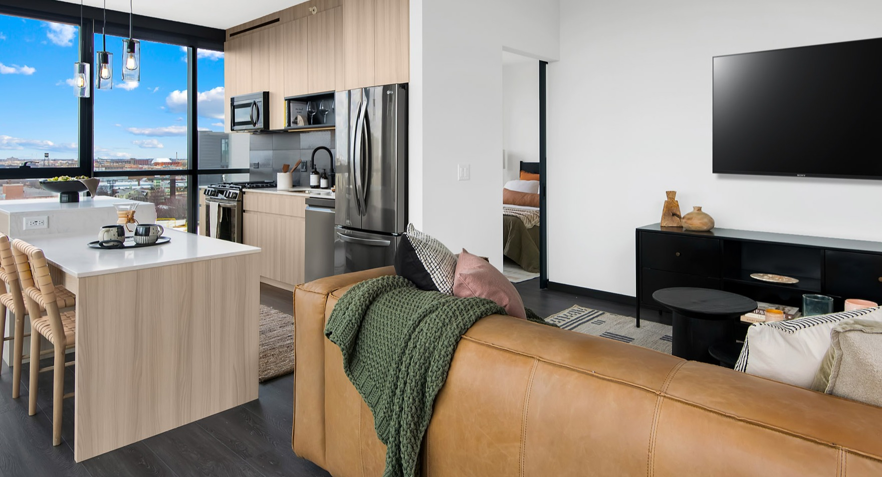 Modern open-concept kitchen and living area at Parq Fulton in Chicago, featuring a large island, comfortable seating, and city views