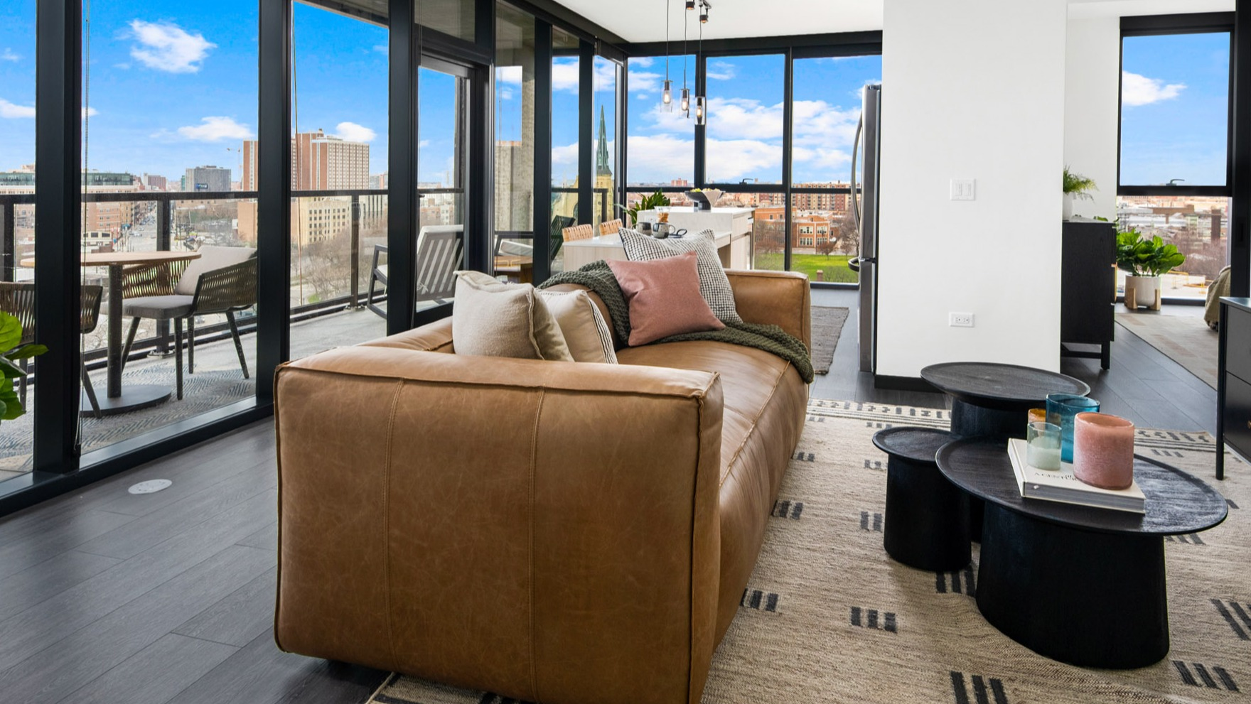 Spacious living room at Parq Fulton in Chicago, featuring a comfortable leather sofa, elegant decor, and a large balcony with city views