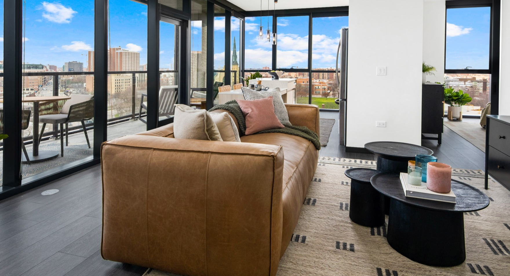 Spacious living room at Parq Fulton in Chicago, featuring a comfortable leather sofa, elegant decor, and a large balcony with city views