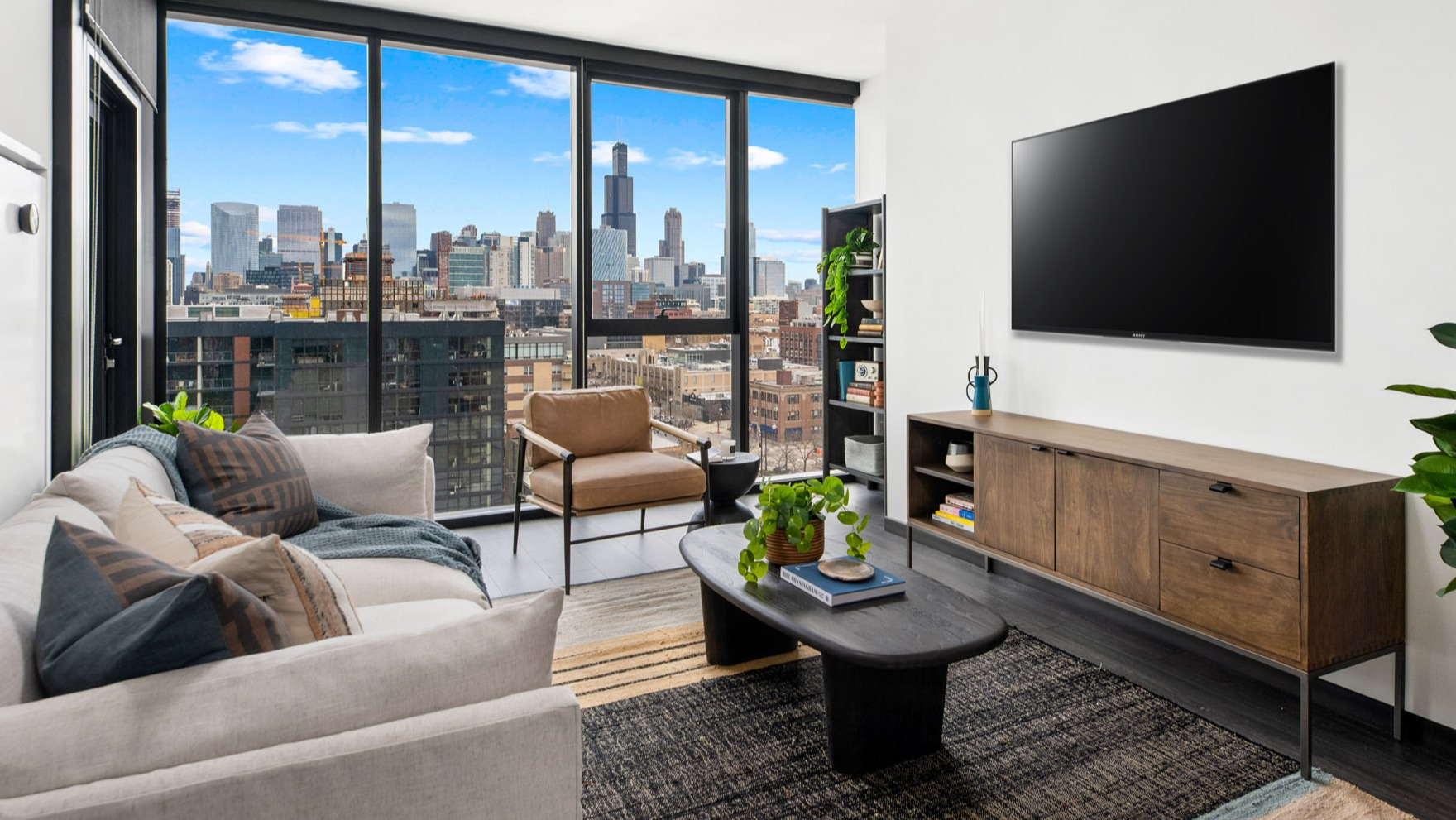 Contemporary living room at Parq Fulton in Chicago, featuring a large TV, comfortable sofa, and panoramic city skyline views