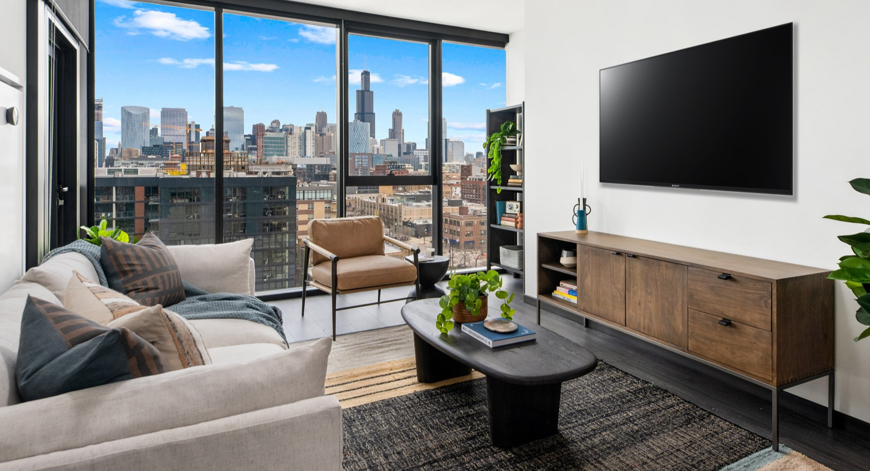 Contemporary living room at Parq Fulton in Chicago, featuring a large TV, comfortable sofa, and panoramic city skyline views