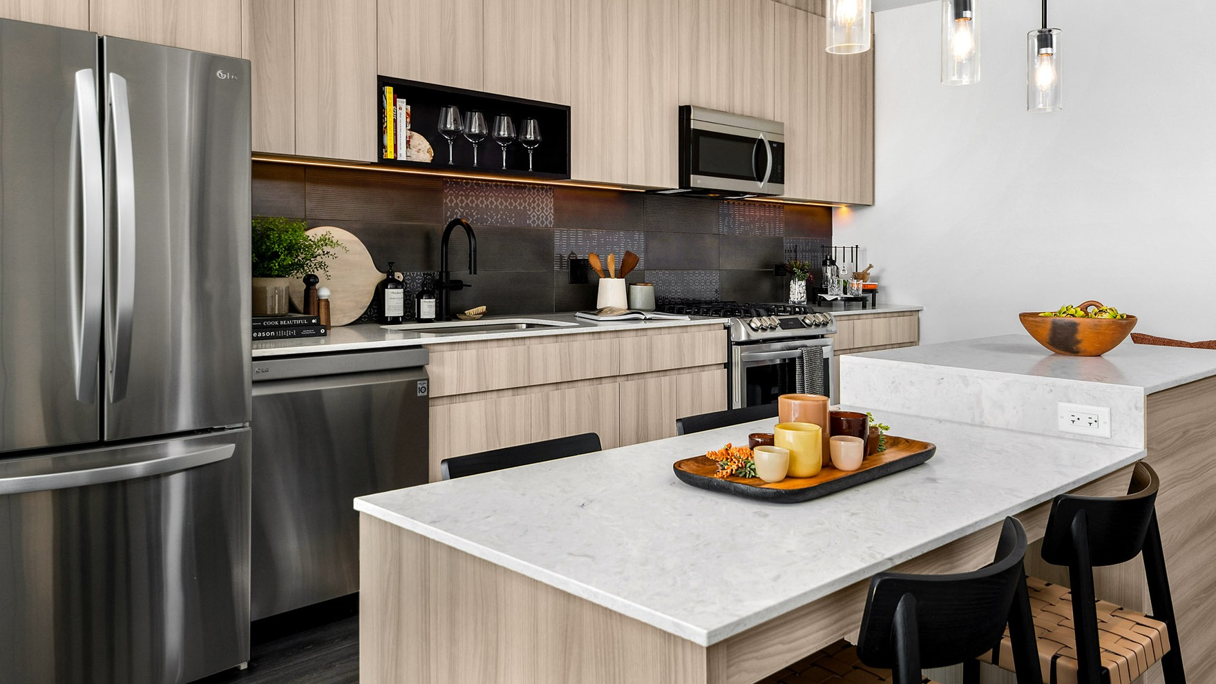 Gourmet apartment kitchen at Parq Fulton in Chicago, featuring light wood cabinetry, stainless steel appliances, and a large island