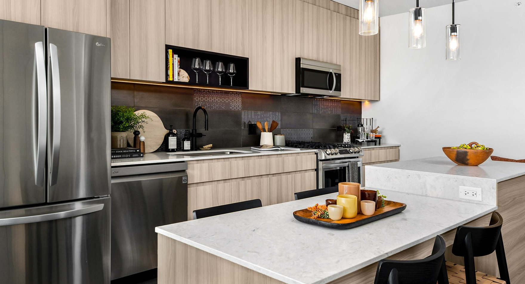 Gourmet apartment kitchen at Parq Fulton in Chicago, featuring light wood cabinetry, stainless steel appliances, and a large island