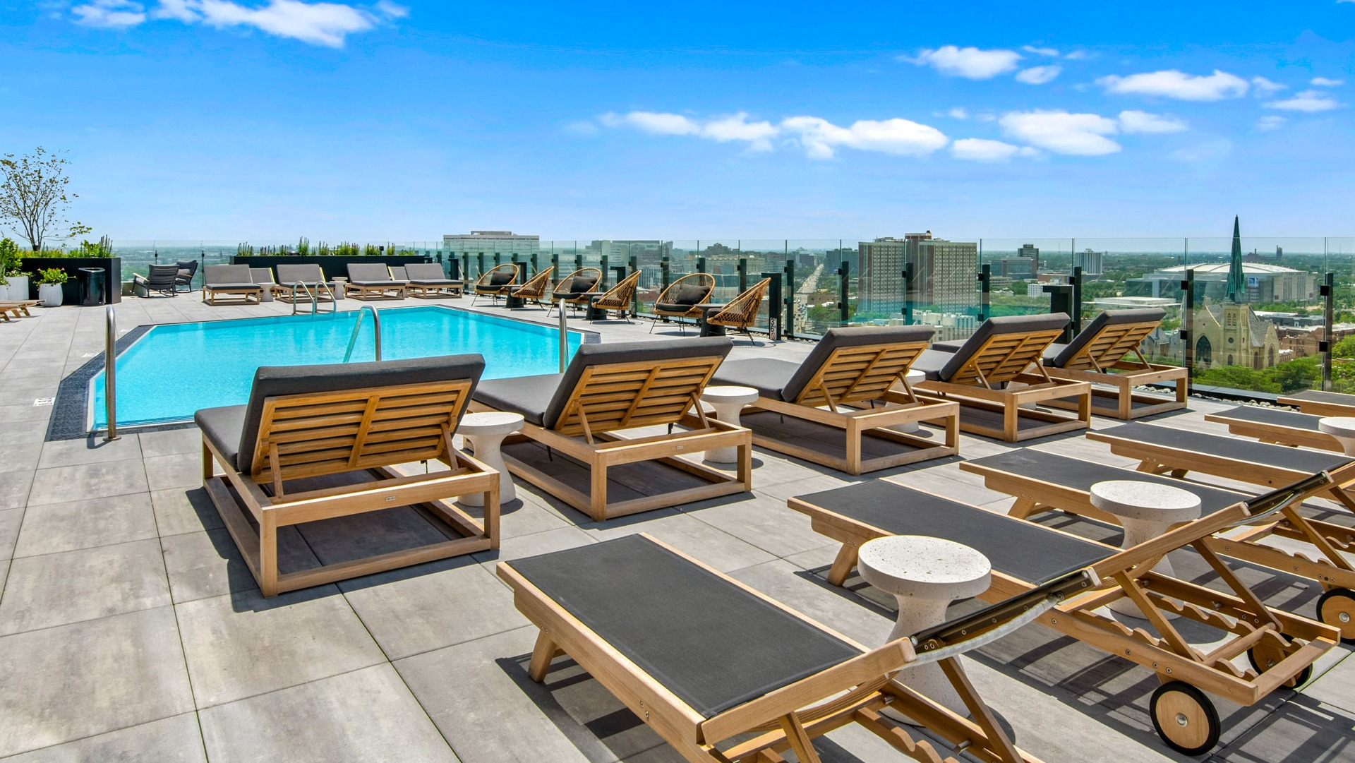 Luxurious pool deck at Parq Fulton in Chicago, featuring numerous lounge chairs for sunbathing and expansive city views