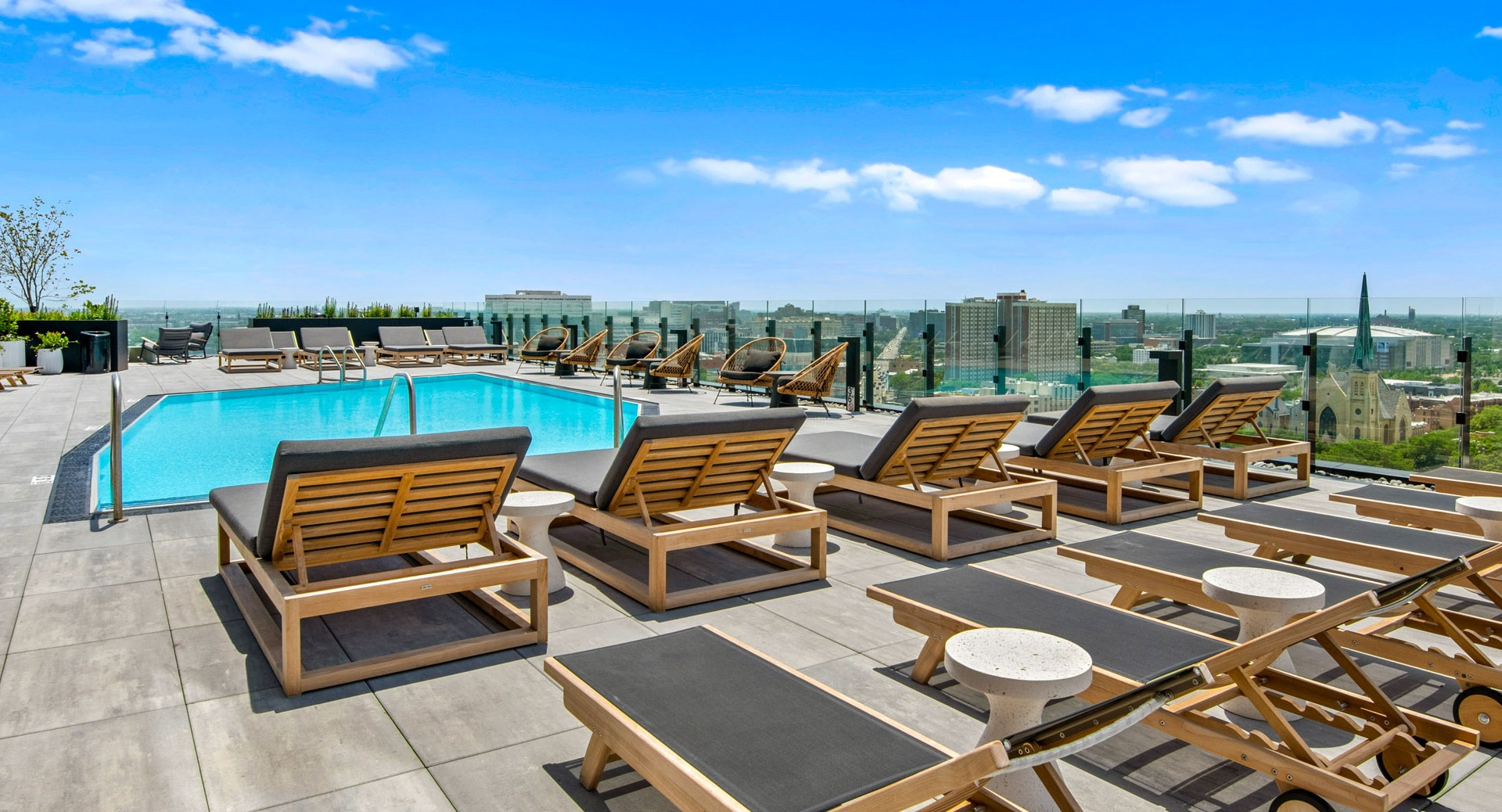 Luxurious pool deck at Parq Fulton in Chicago, featuring numerous lounge chairs for sunbathing and expansive city views