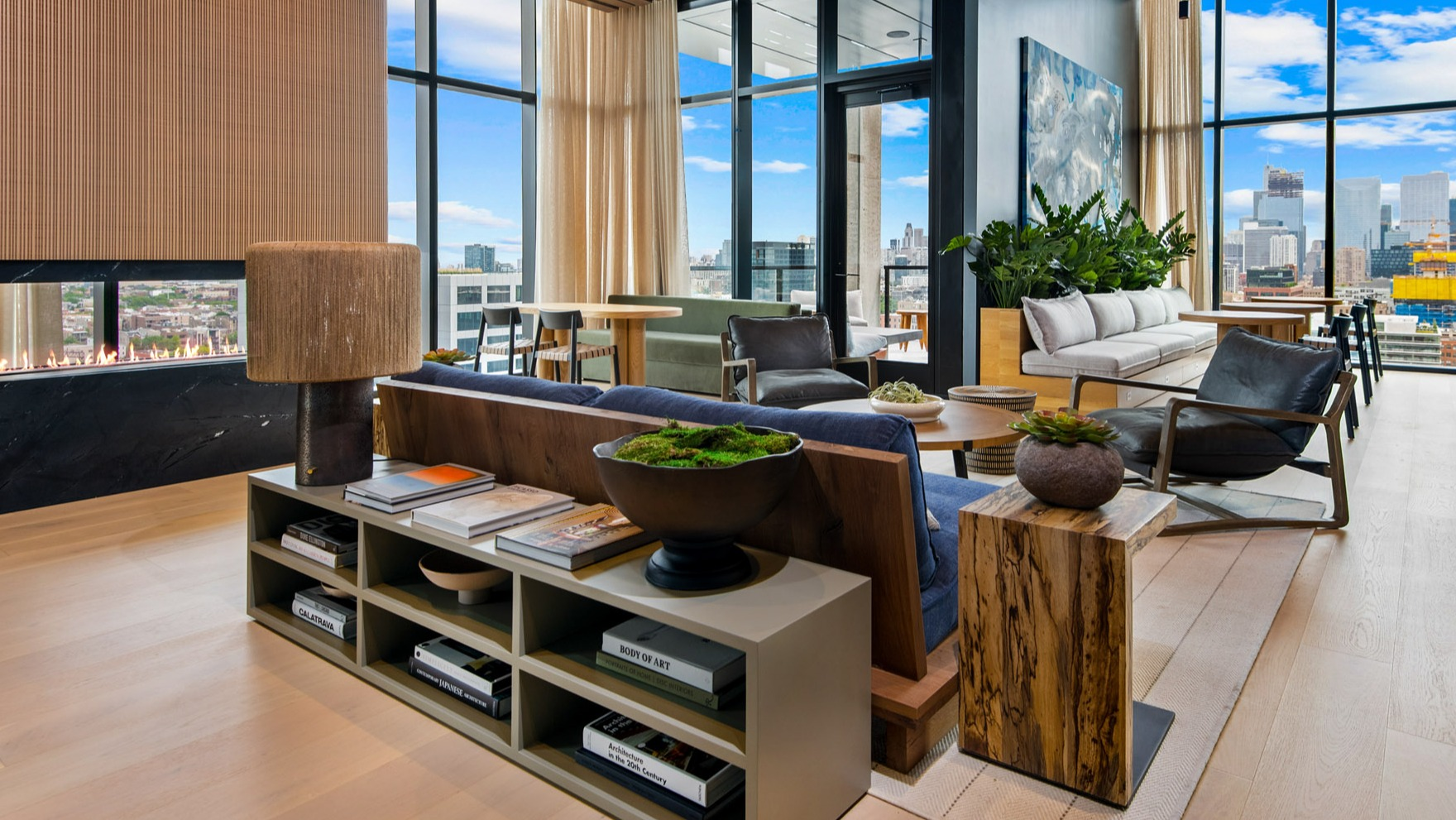 Elegant resident lounge at Parq Fulton in Chicago, featuring a modern fireplace, diverse seating, and floor-to-ceiling windows with city views