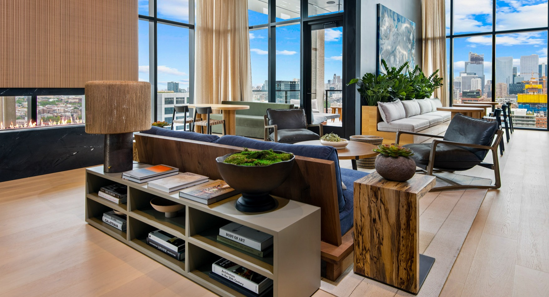 Elegant resident lounge at Parq Fulton in Chicago, featuring a modern fireplace, diverse seating, and floor-to-ceiling windows with city views