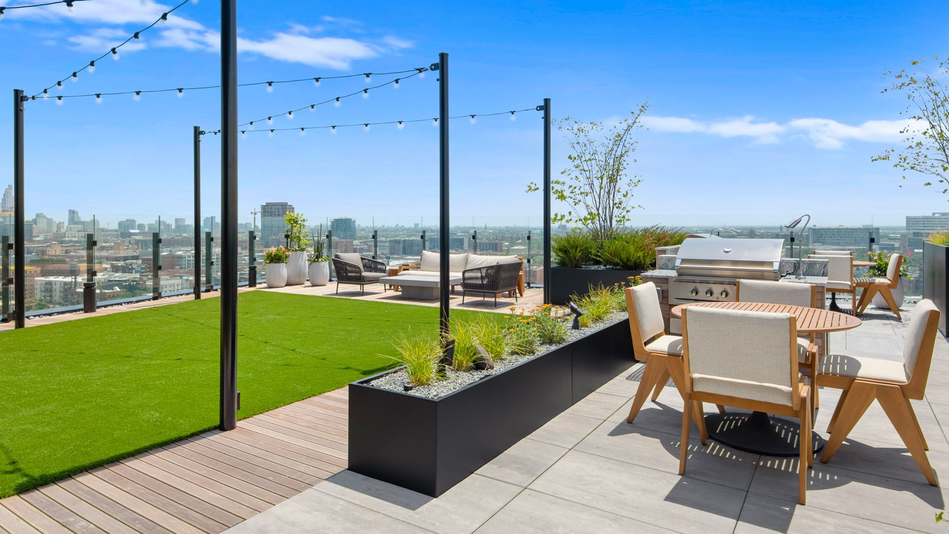 Expansive rooftop deck at Parq Fulton in Chicago, featuring an outdoor kitchen with grills, dining areas, and lush green spaces with city views