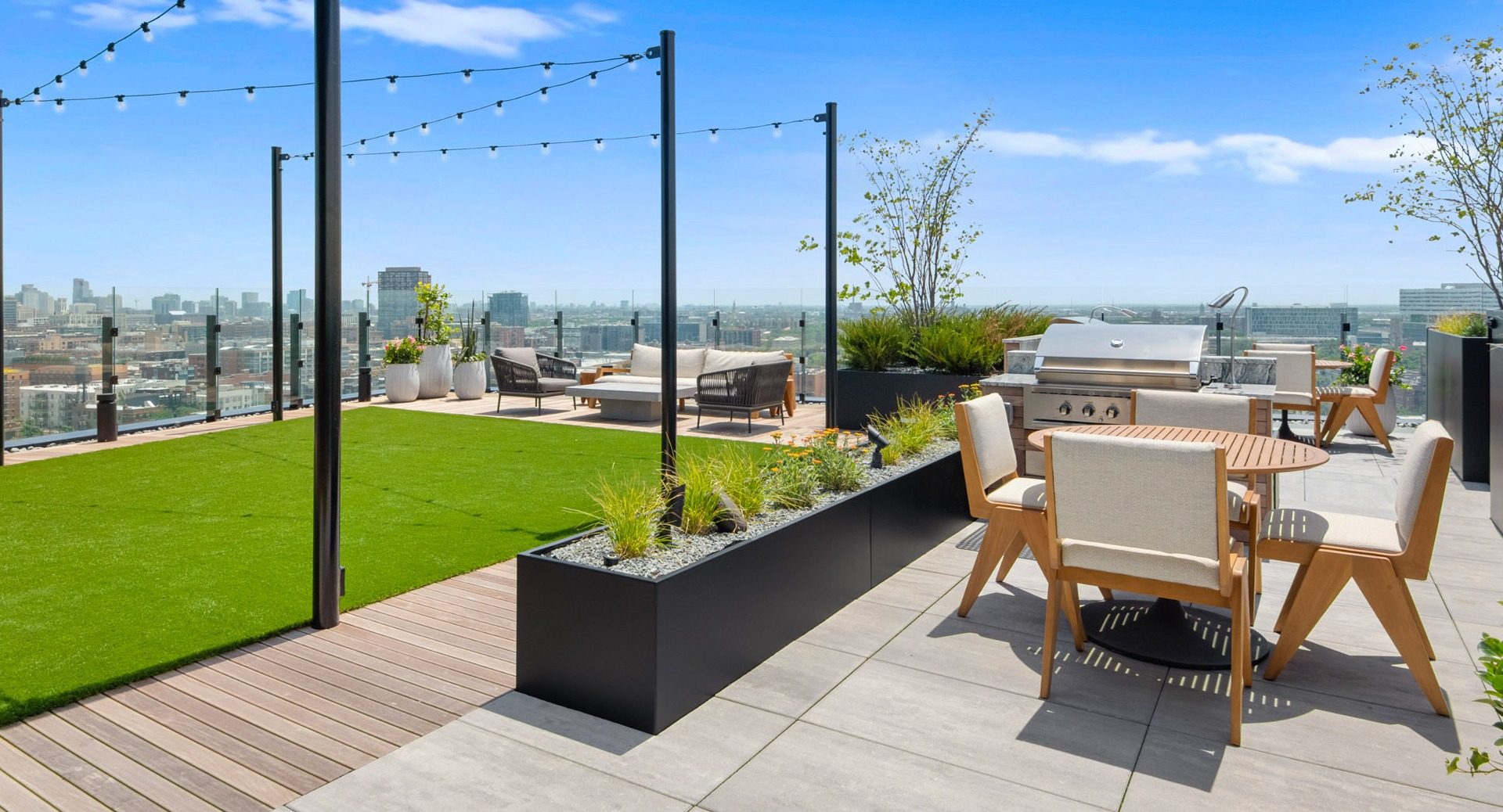 Expansive rooftop deck at Parq Fulton in Chicago, featuring an outdoor kitchen with grills, dining areas, and lush green spaces with city views