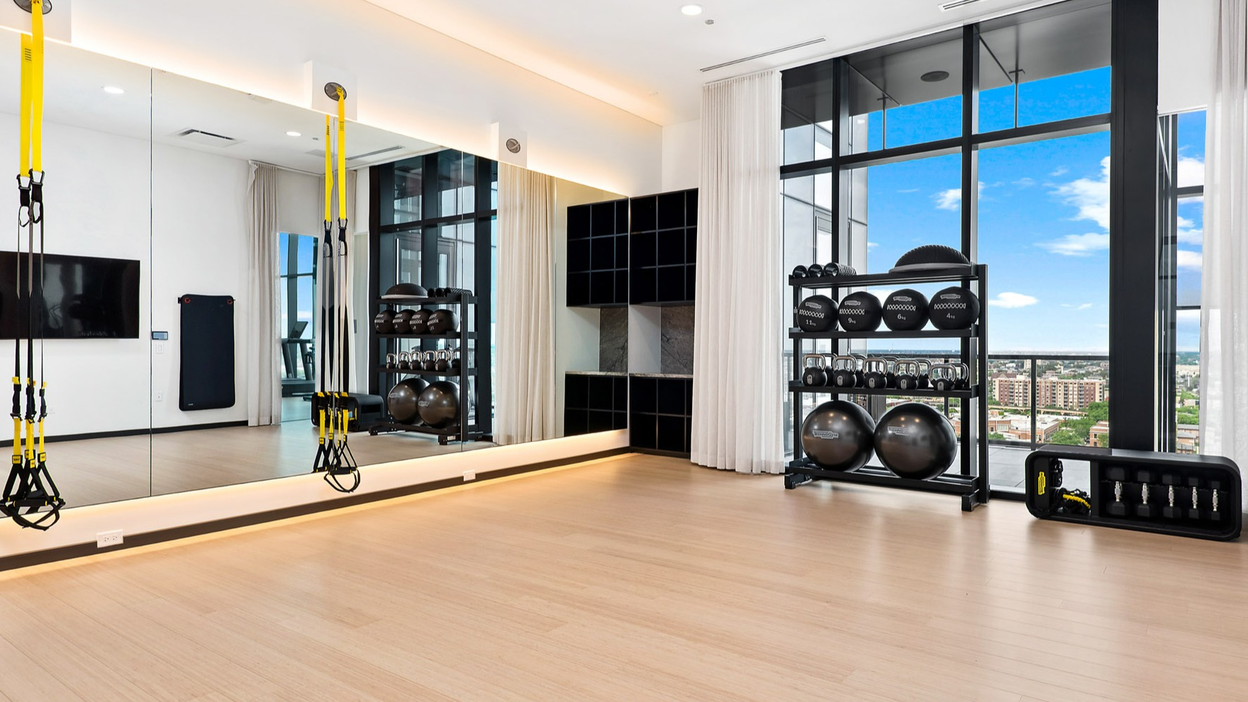 Spacious yoga and fitness studio at Parq Fulton in Chicago, featuring TRX equipment, free weights, and large mirrors