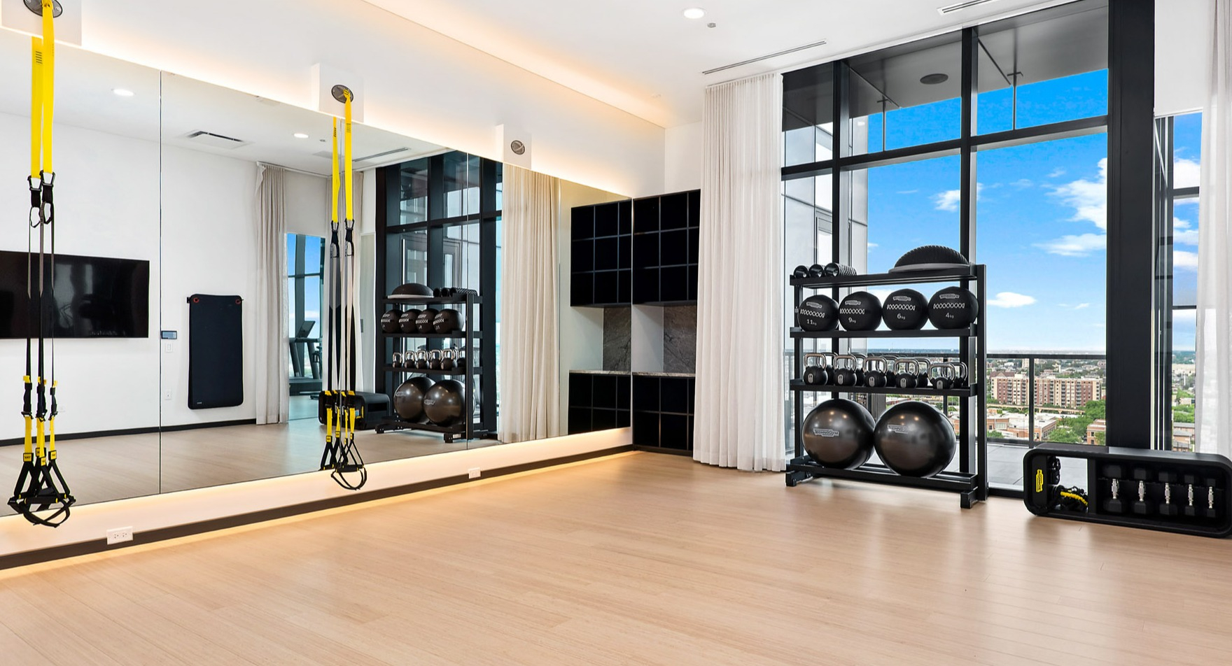 Spacious yoga and fitness studio at Parq Fulton in Chicago, featuring TRX equipment, free weights, and large mirrors