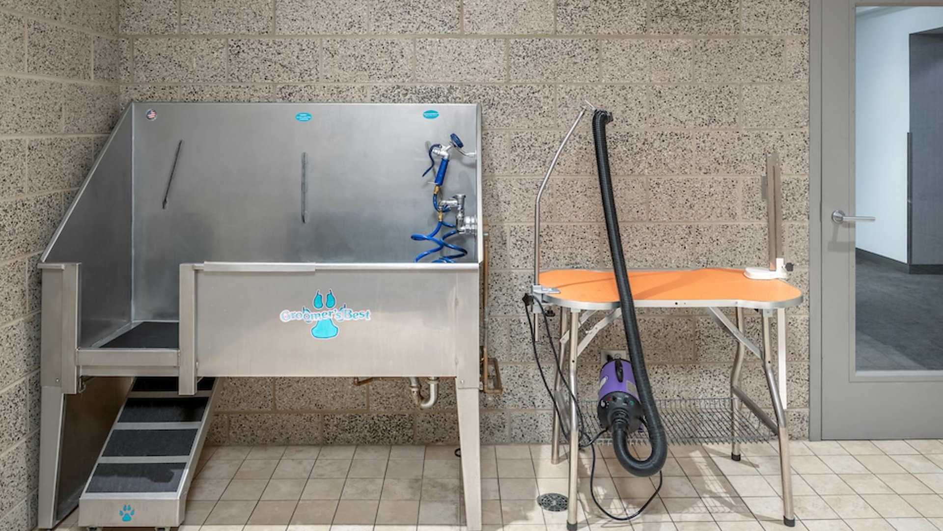 Pet wash and grooming station with stainless steel tub, drying table, and tiled flooring at Optima Signature apartments in Chicago