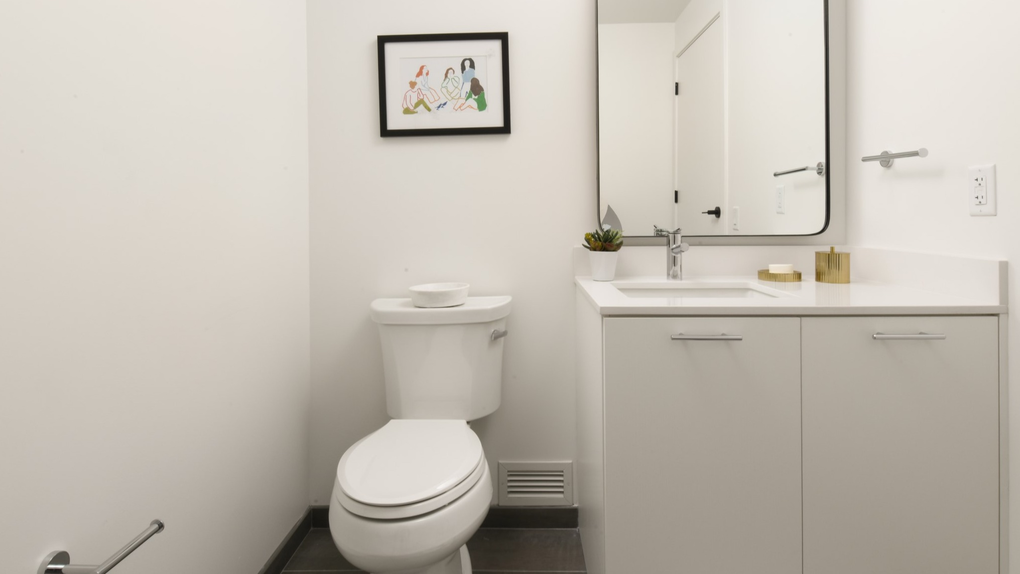 Bright and modern apartment bathroom at Porte Apartments Chicago, featuring a white vanity, sleek mirror, and minimalist decor