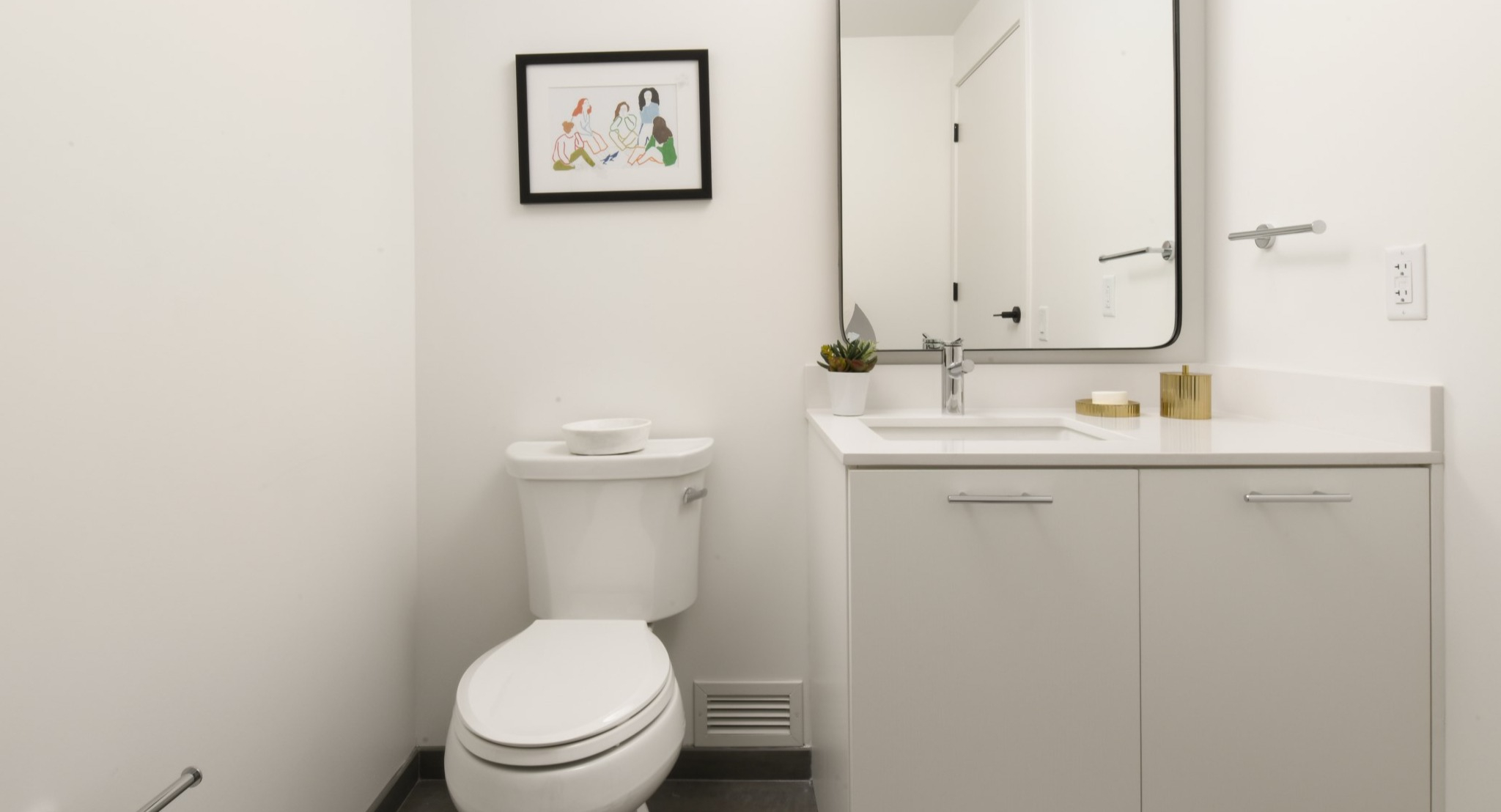 Bright and modern apartment bathroom at Porte Apartments Chicago, featuring a white vanity, sleek mirror, and minimalist decor