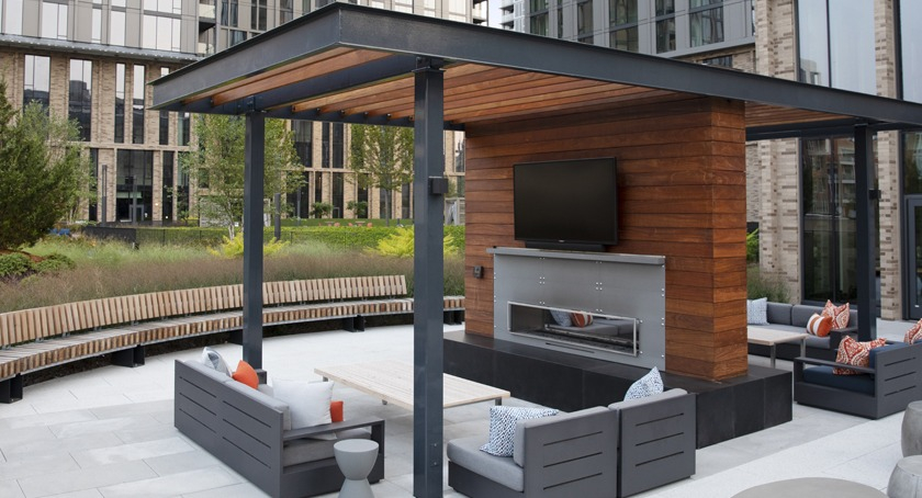 Expansive outdoor courtyard lounge at Porte Apartments Chicago, featuring a modern fireplace, ample seating, and a lush landscape