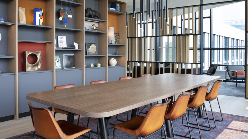 Elegant dining and lounge area at Porte Apartments Chicago, featuring a long communal table, built-in shelving, and comfortable seating