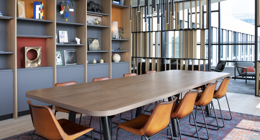 Elegant dining and lounge area at Porte Apartments Chicago, featuring a long communal table, built-in shelving, and comfortable seating