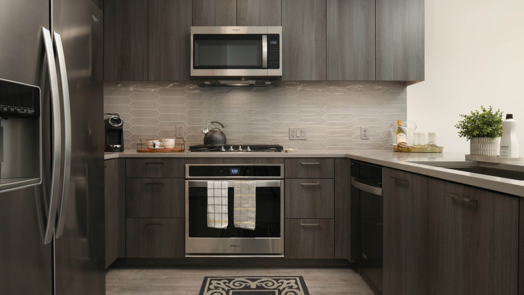 Modern apartment kitchen at Porte Apartments Chicago, featuring sleek gray cabinets, stainless steel appliances, and stylish backsplash