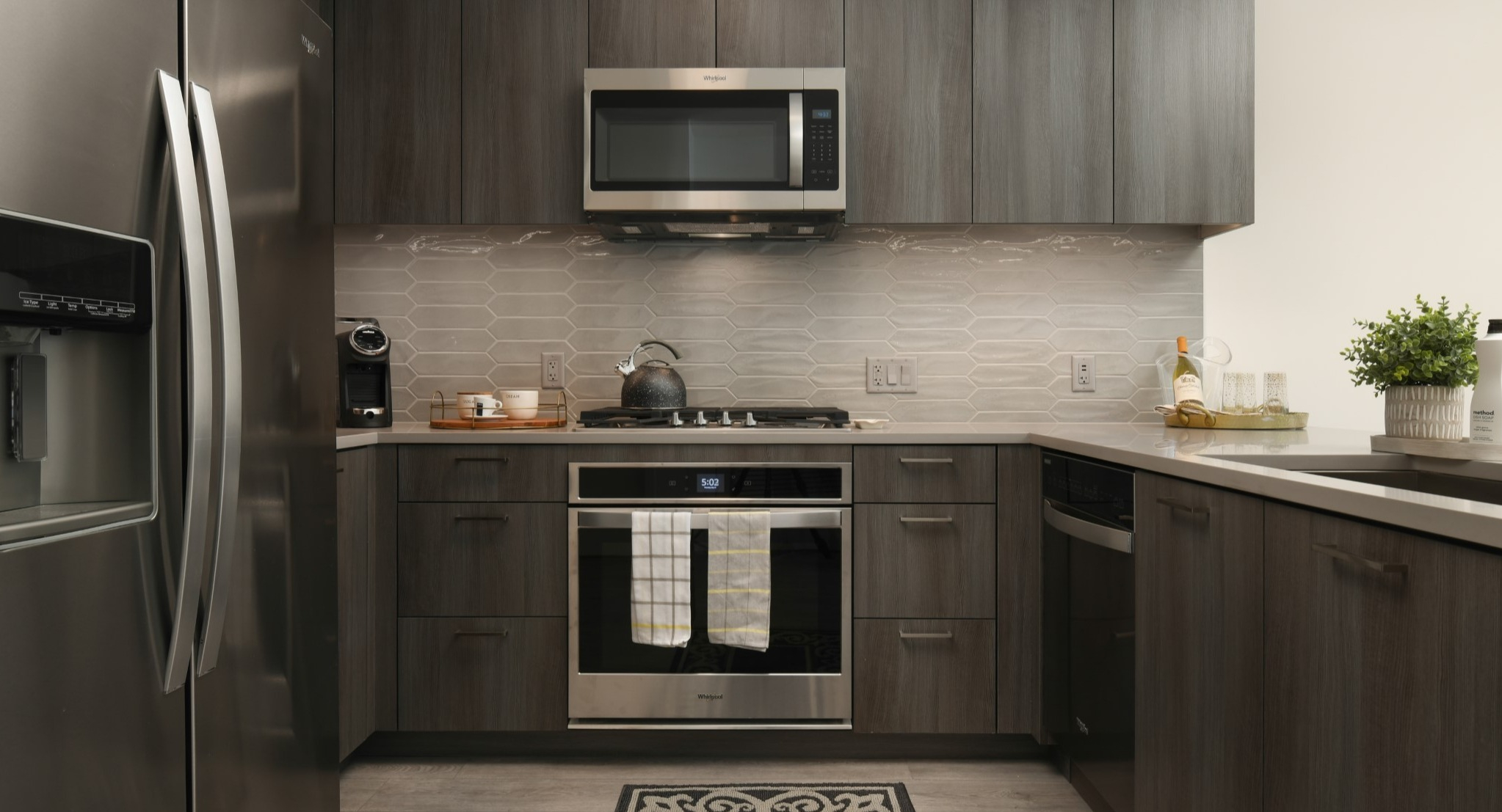 Modern apartment kitchen at Porte Apartments Chicago, featuring sleek gray cabinets, stainless steel appliances, and stylish backsplash