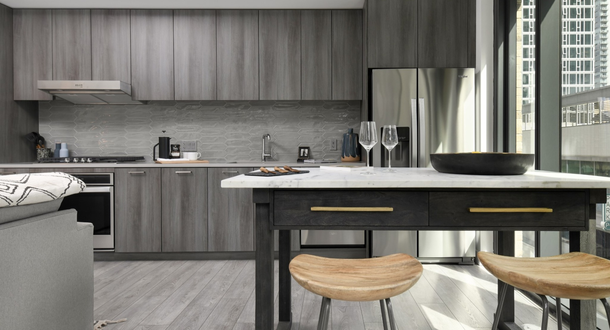 Modern apartment kitchen at Porte Apartments Chicago, featuring elegant wood-grain cabinets, stainless steel appliances, and an island