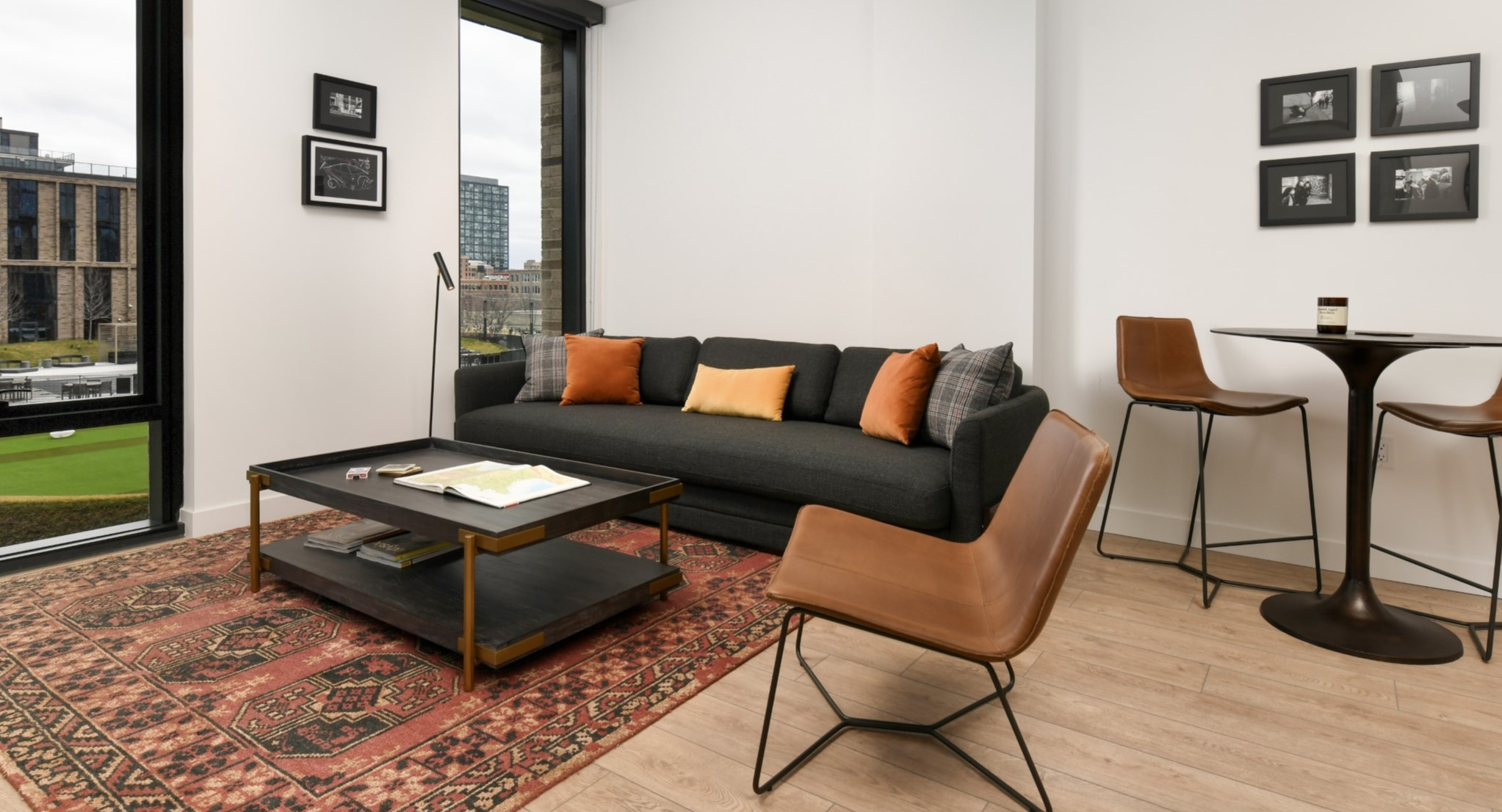 Stylish apartment living room at Porte Apartments Chicago, featuring a comfortable sofa, accent chair, and a vibrant area rug with large windows
