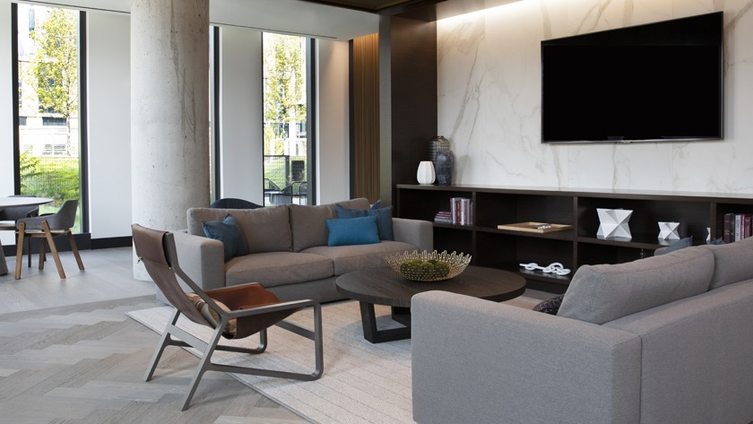 Modern resident lounge at Porte Apartments Chicago, featuring comfortable sofas, a large TV, and elegant marble-accented walls